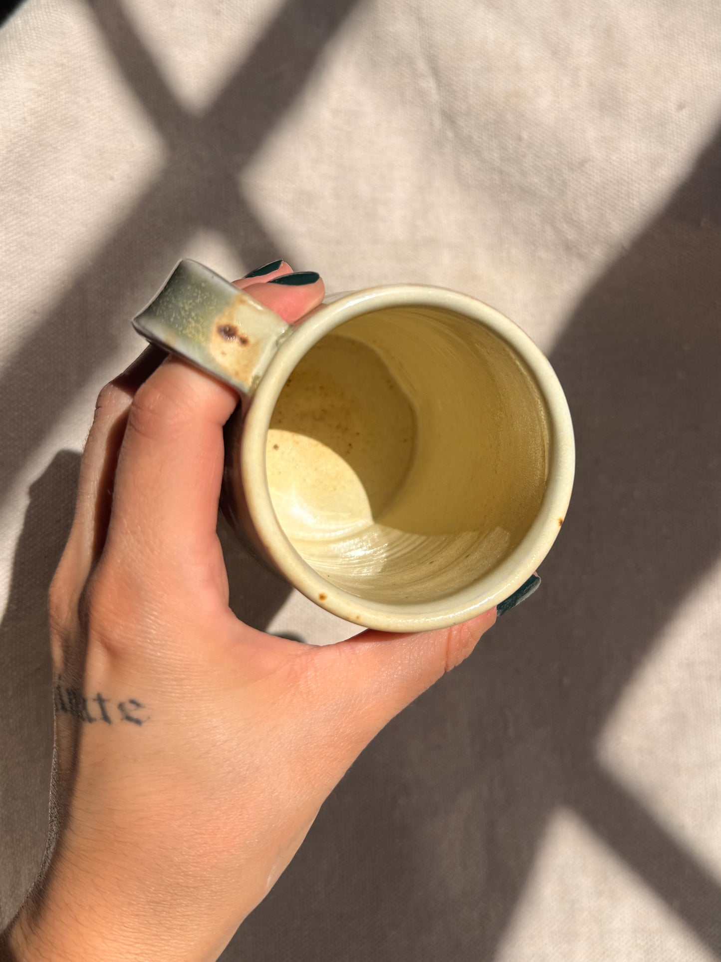 Hand holding a yellow ceramic mug with a textured interior against a neutral background