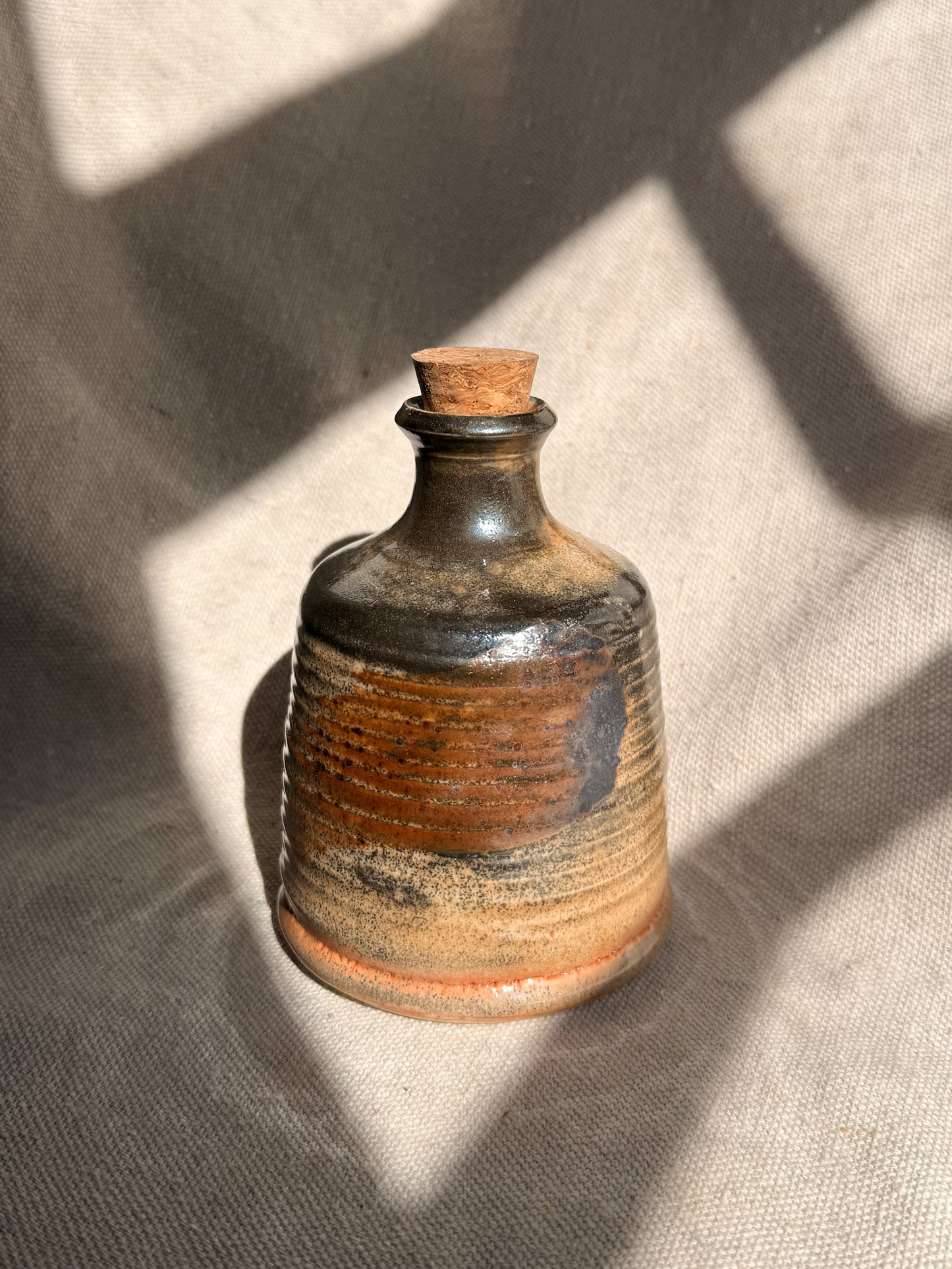 Small ceramic bottle with a cork on a textured surface