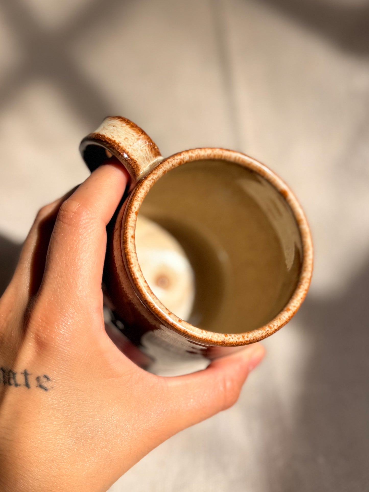 brown ceramic mug with red dot and beige interior
