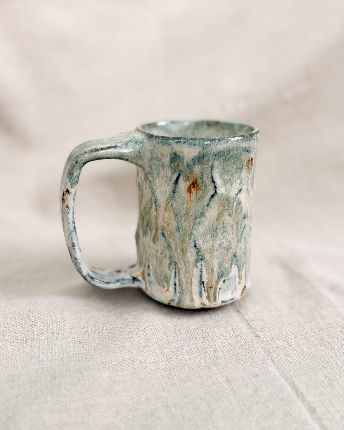 Handmade ceramic mug with a textured surface on a light fabric background