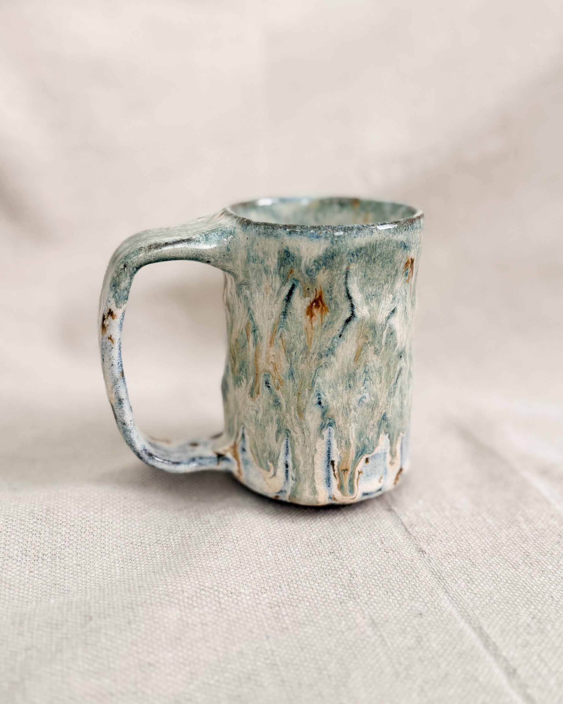 Handmade ceramic mug with a textured surface on a light fabric background