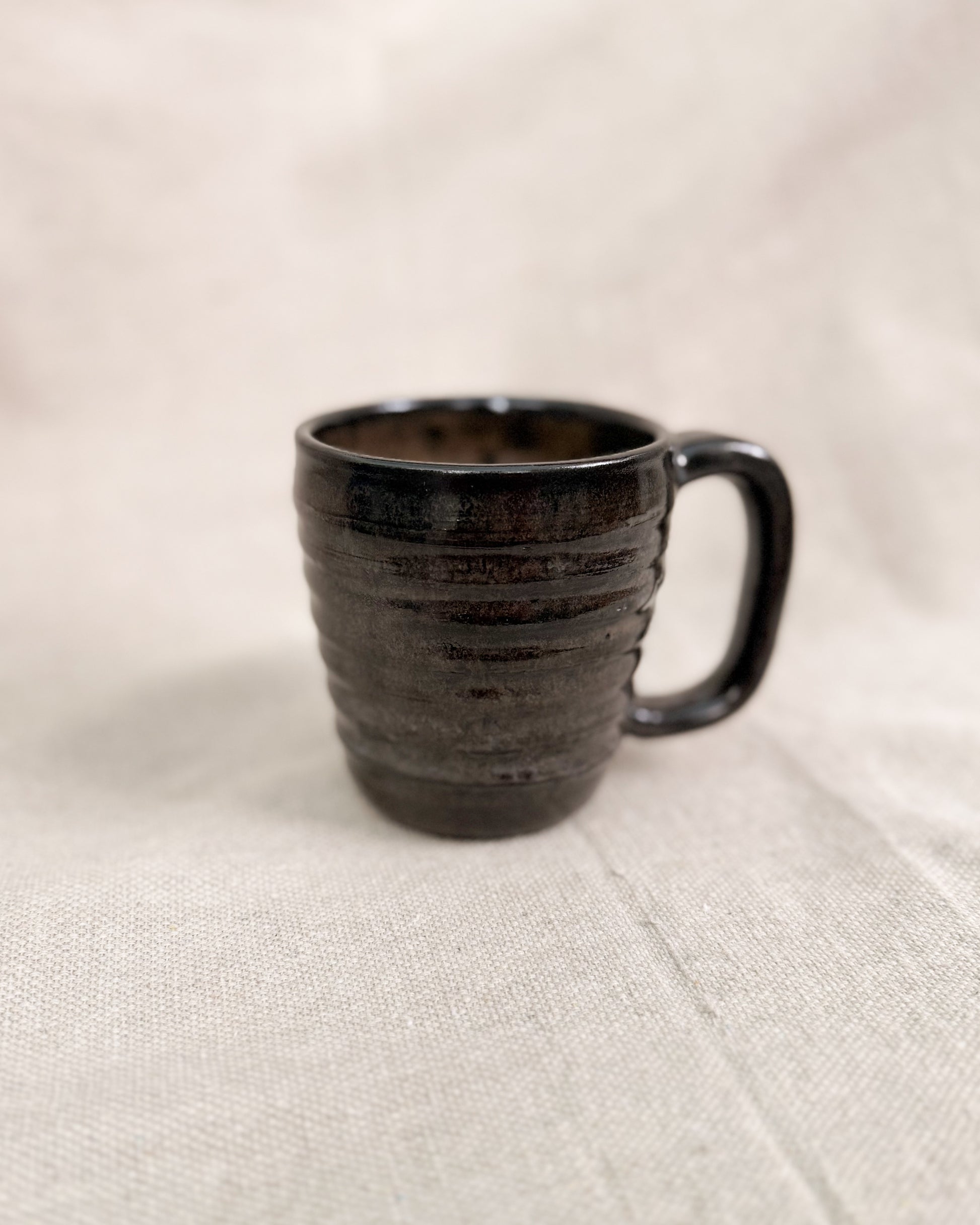 Black ceramic mug on a beige fabric background
