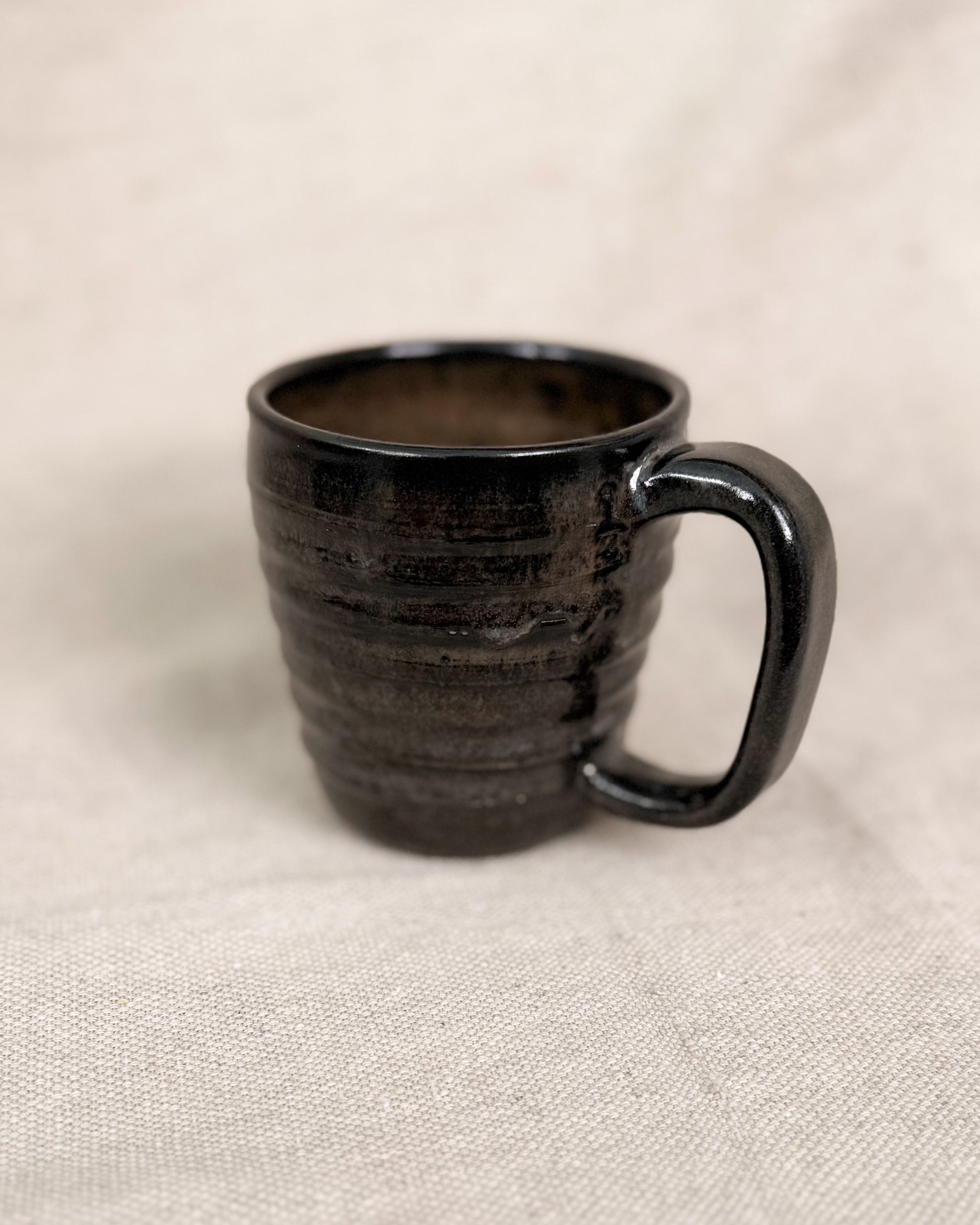 Black ceramic mug on a beige fabric background