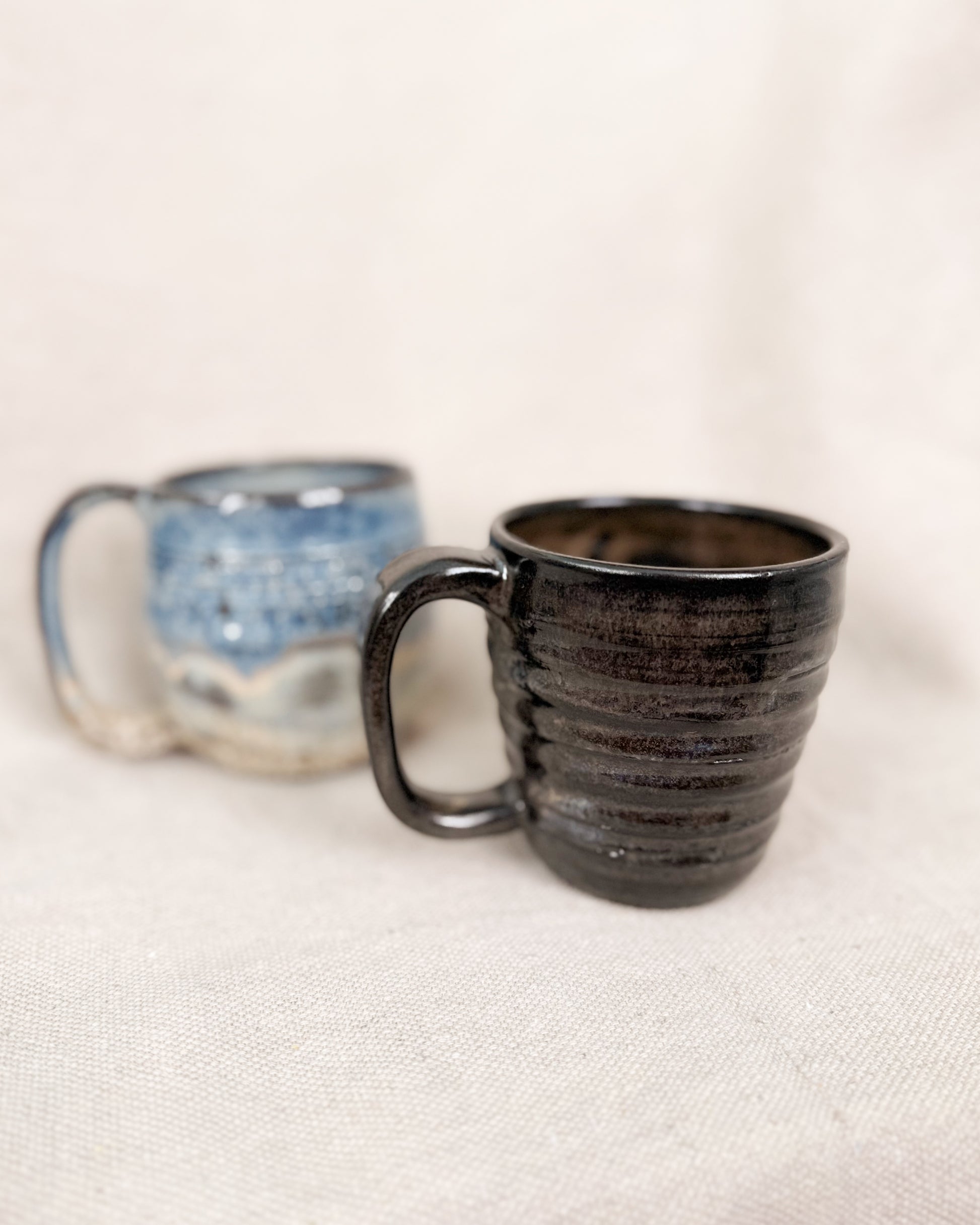 Two ceramic mugs on a light fabric background