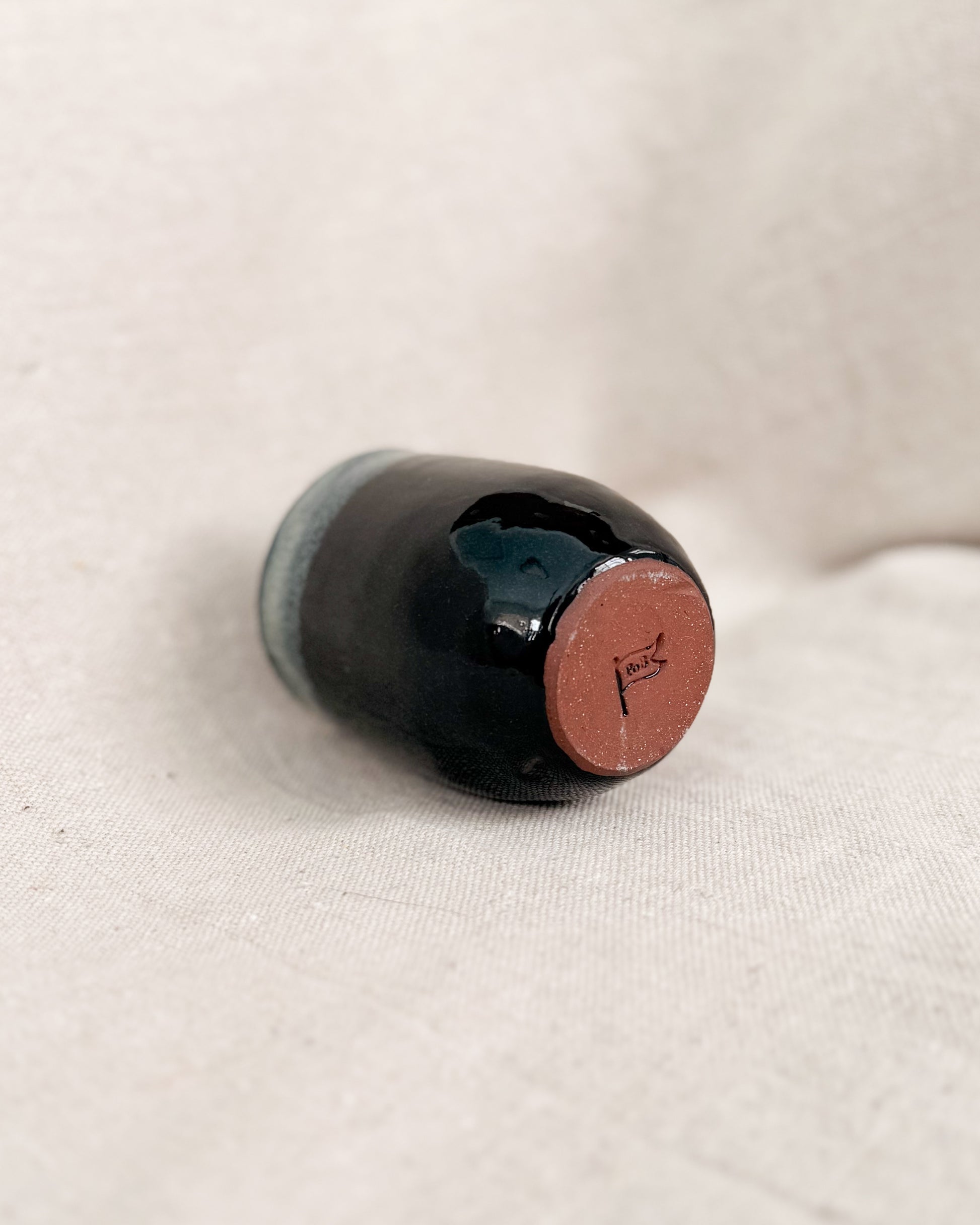 Black ceramic up on a beige fabric background, 6 ounces