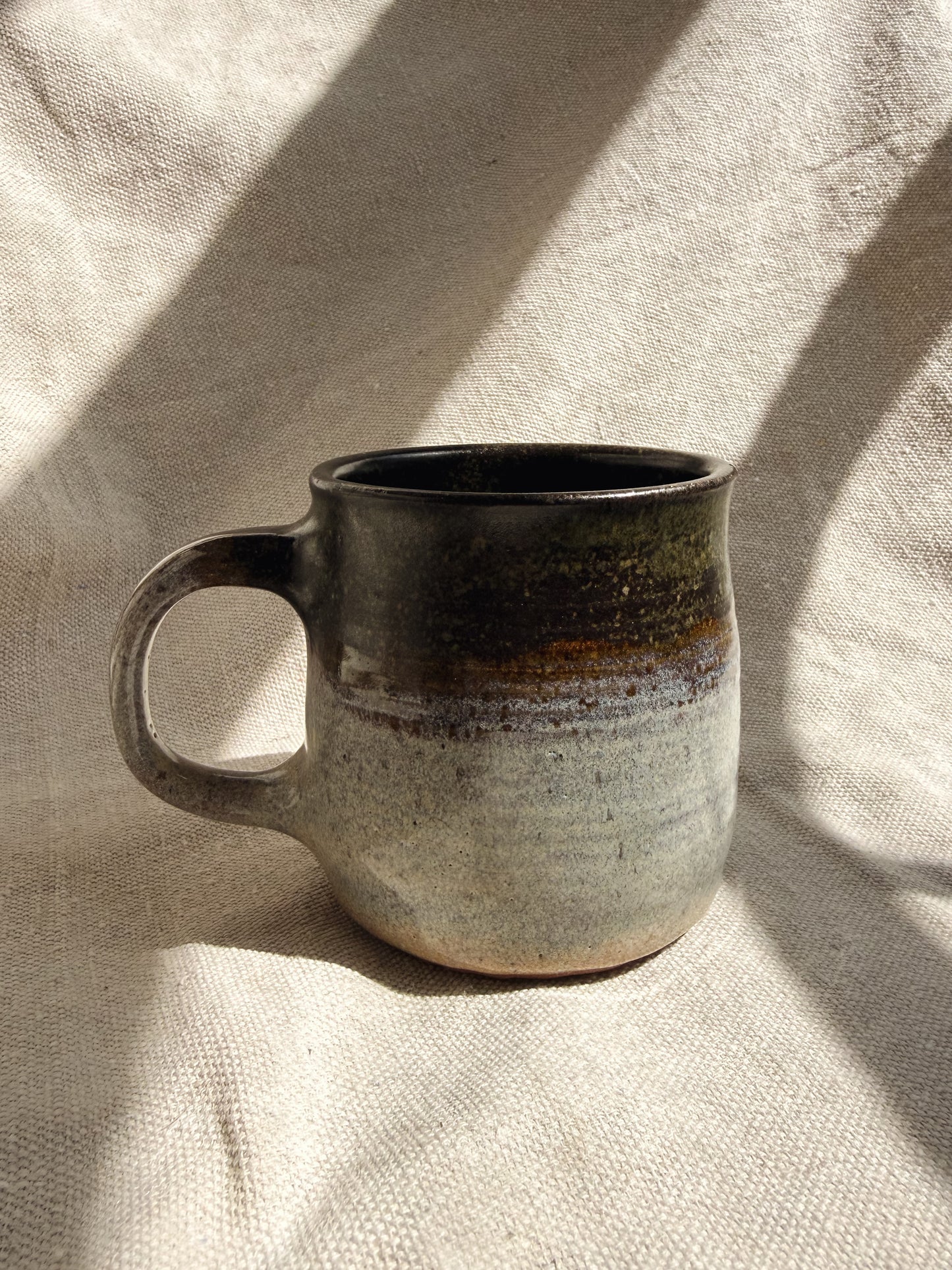 Ceramic mug with a speckled design on a textured beige surface