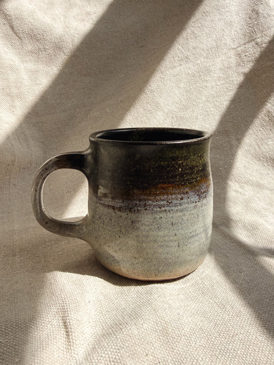 Ceramic mug with a speckled design on a textured beige surface