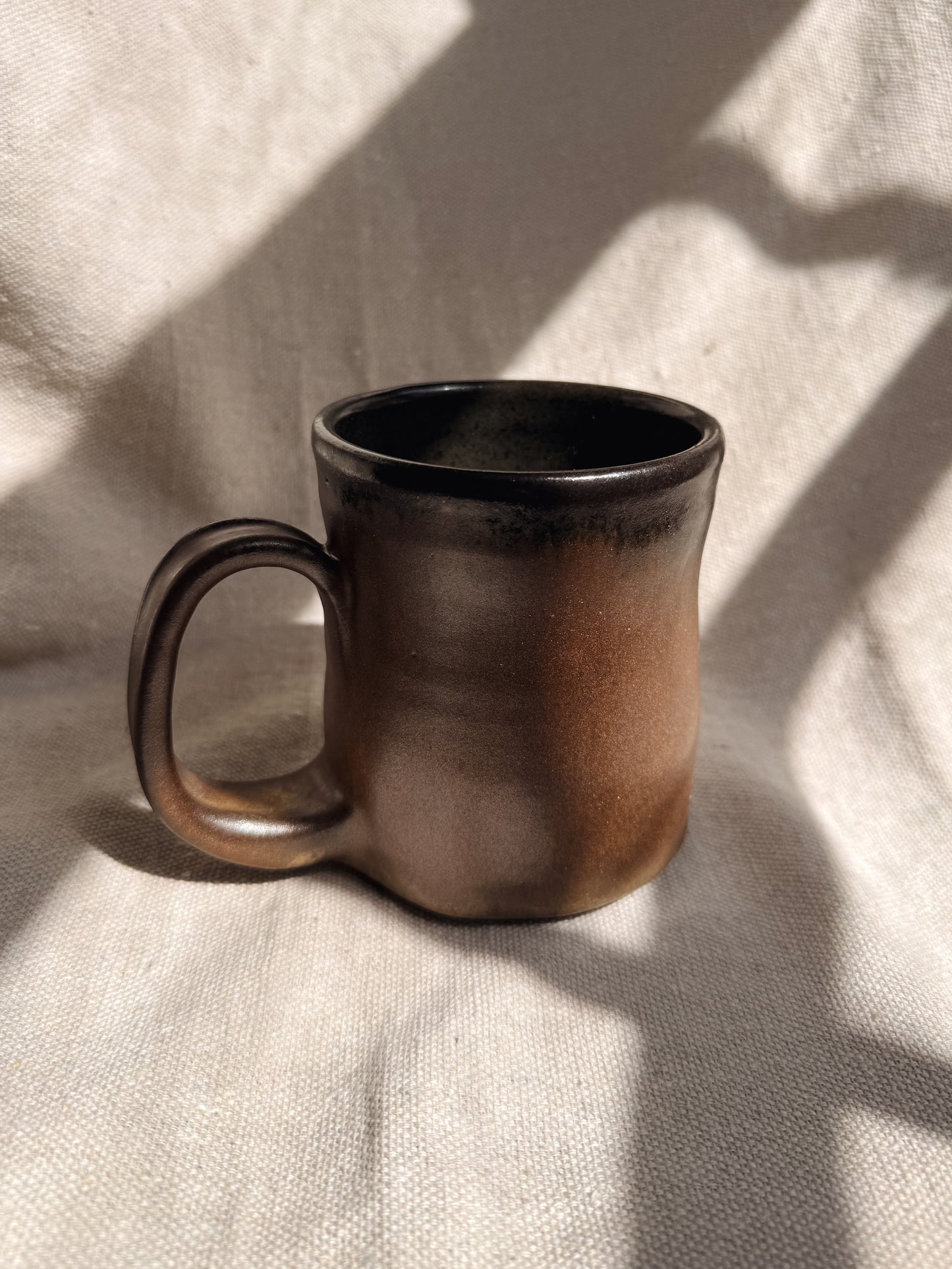 Brown ceramic mug on a textured beige surface