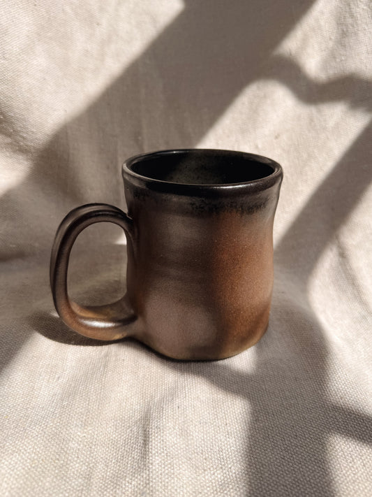 Brown ceramic mug on a textured beige surface