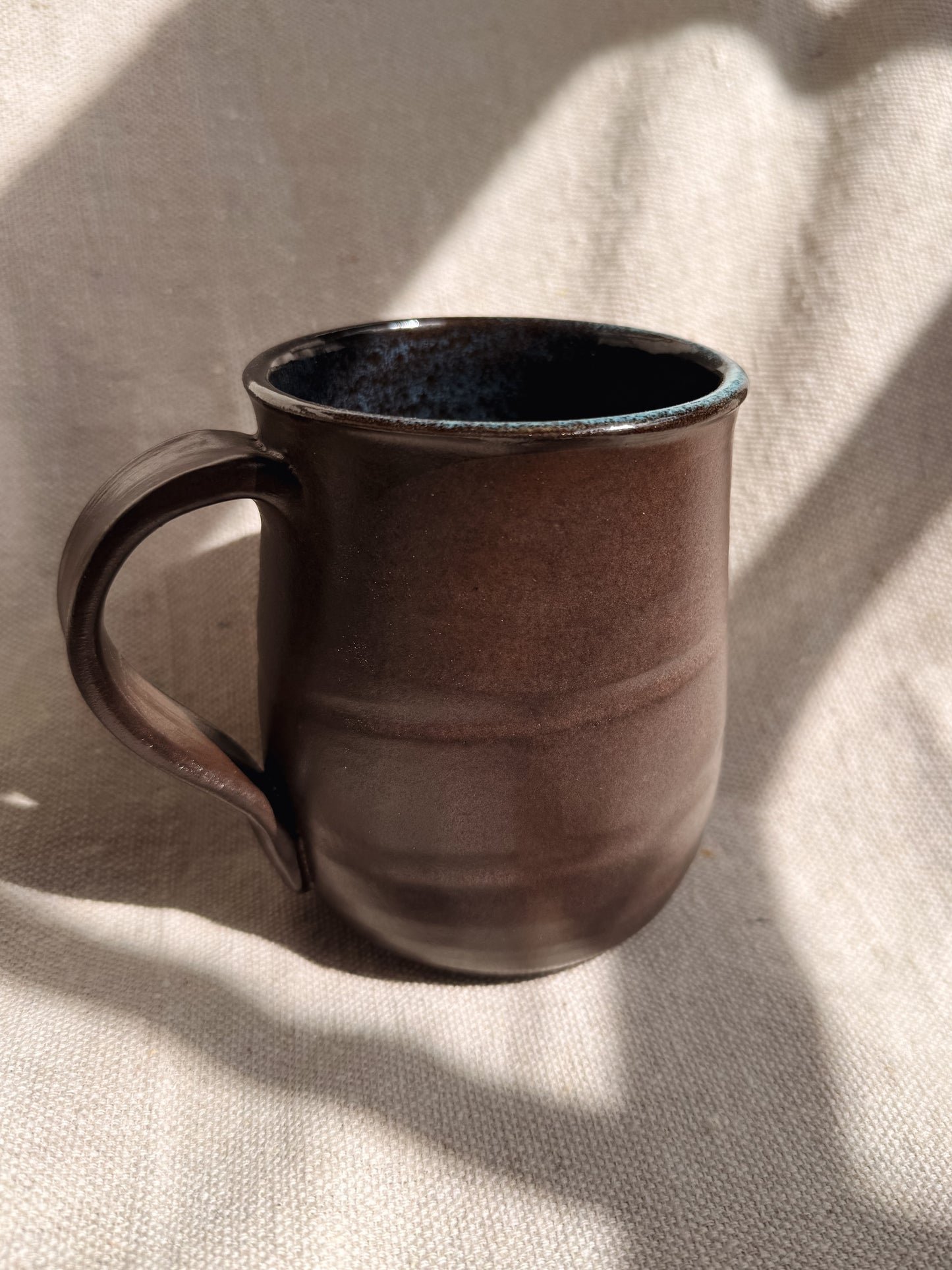 Brown ceramic mug on a textured beige surface