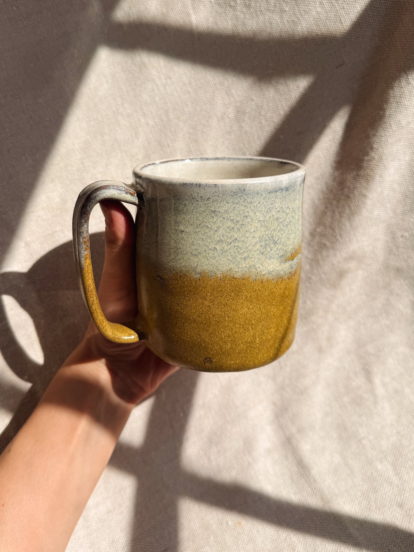 Hand holding a ceramic mug with a gradient design on a neutral background