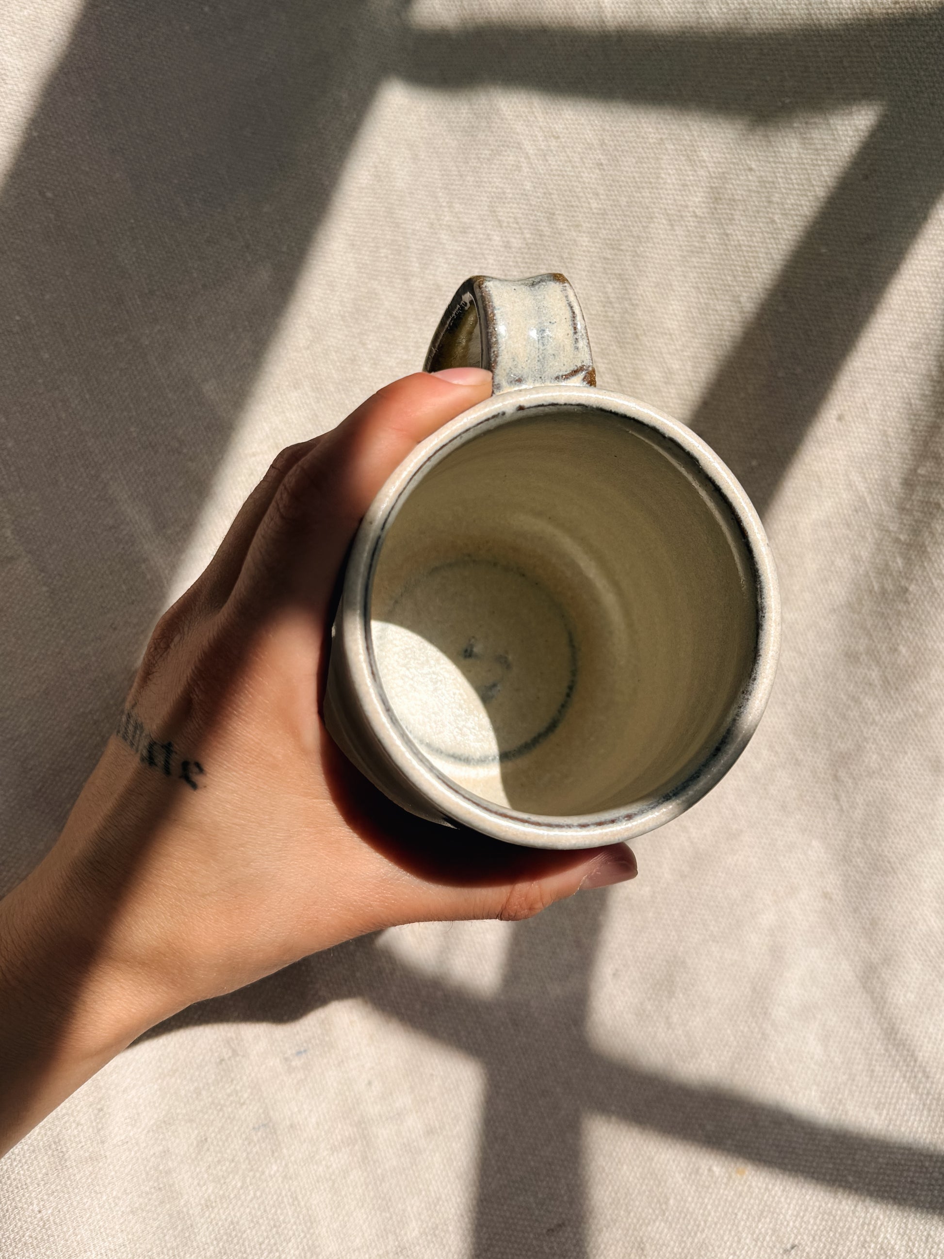 Hand holding a ceramic mug with a neutral background