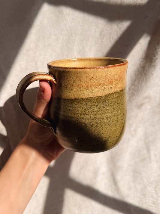 Hand holding a ceramic mug with a gradient finish against a neutral background
