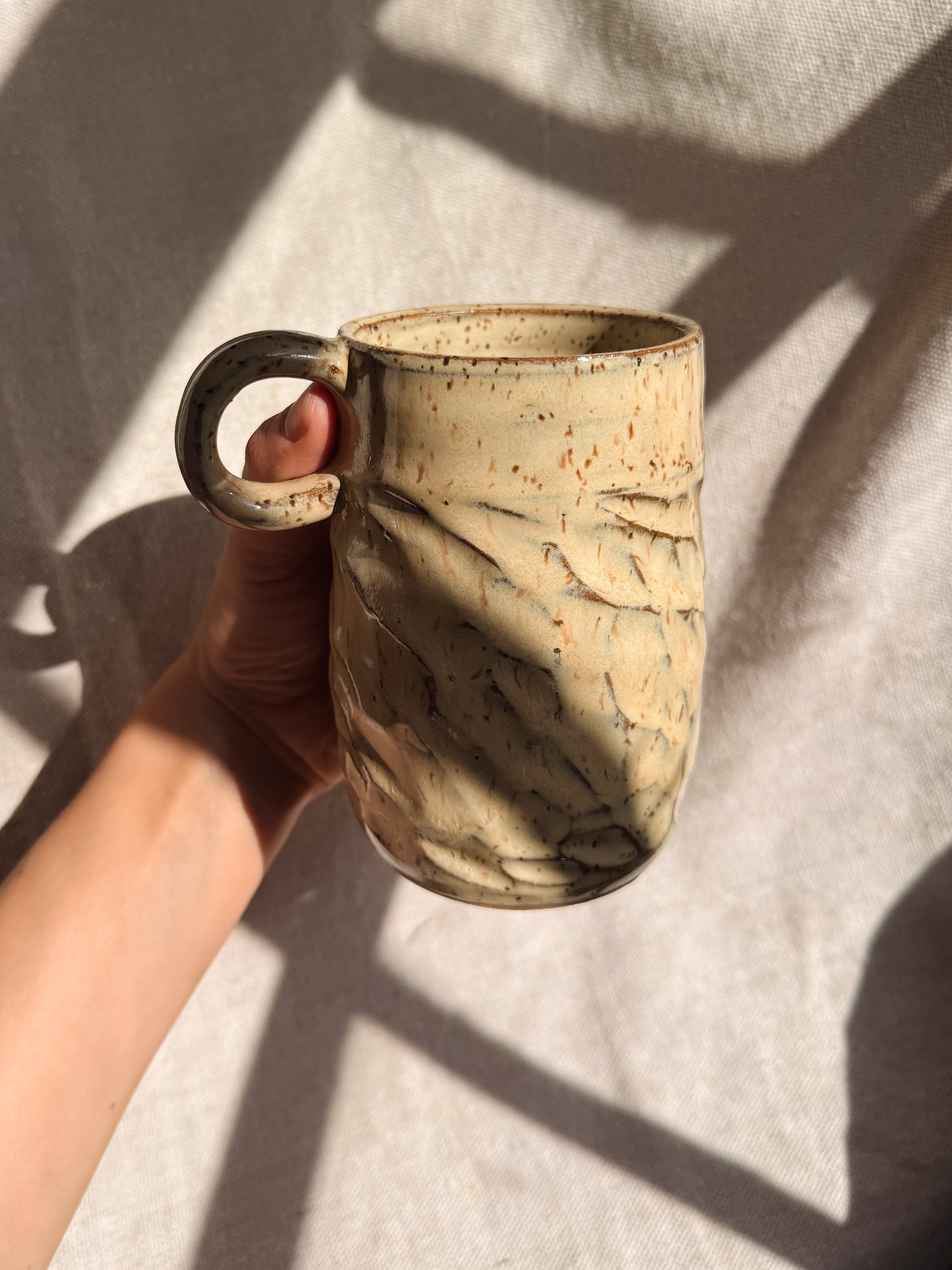 Hand holding a marbled ceramic mug against a neutral background
