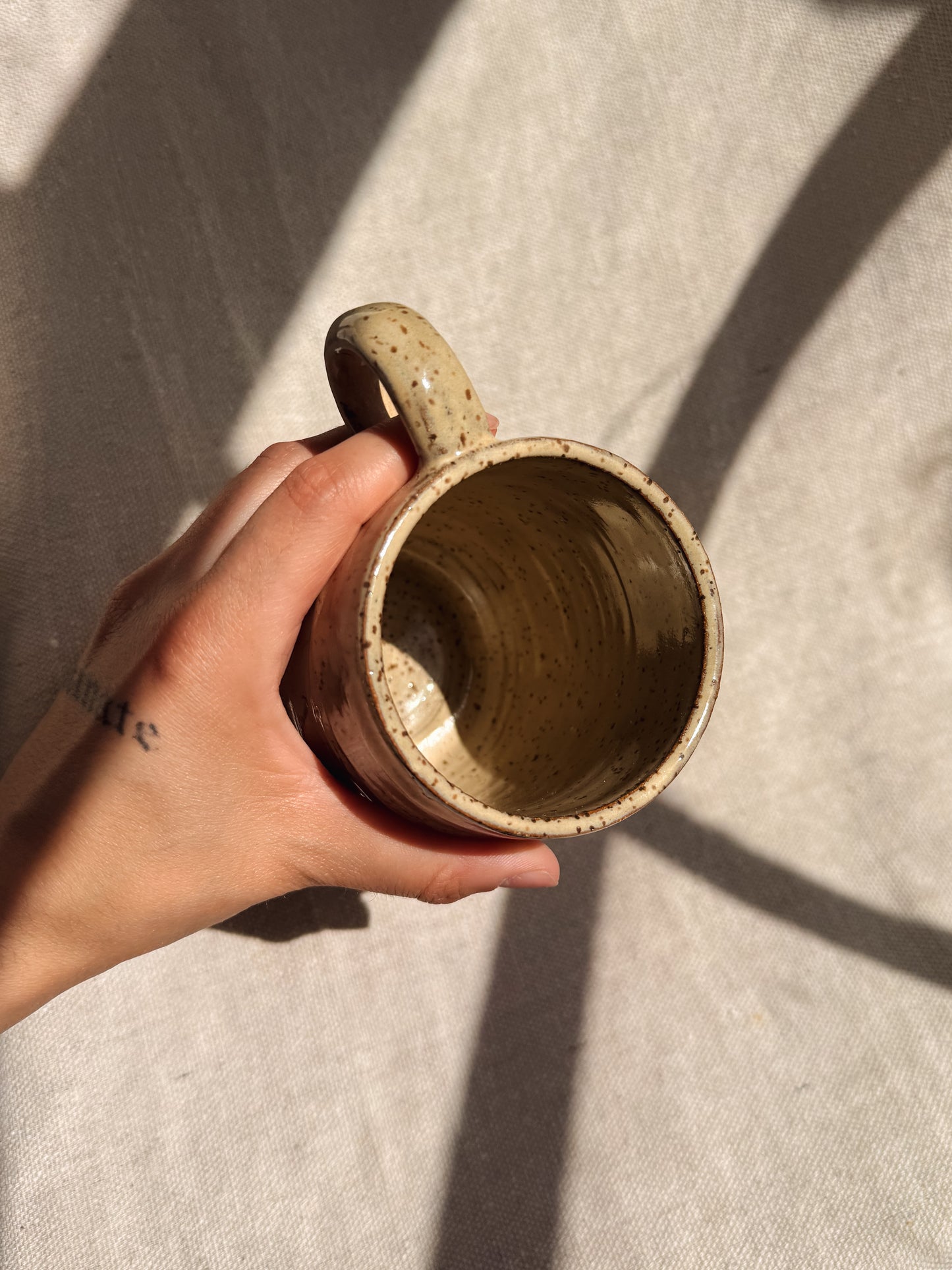 Hand holding a ceramic mug against a neutral background
