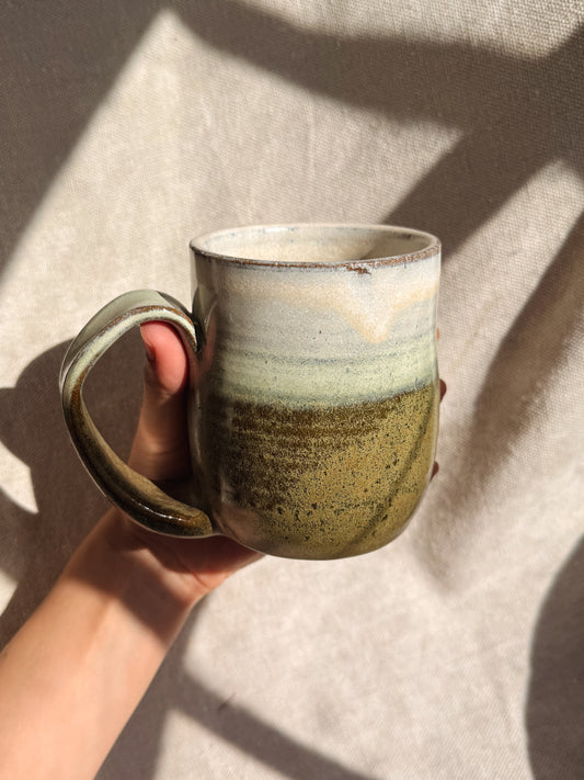 Hand holding a ceramic mug with a textured surface against a neutral background
