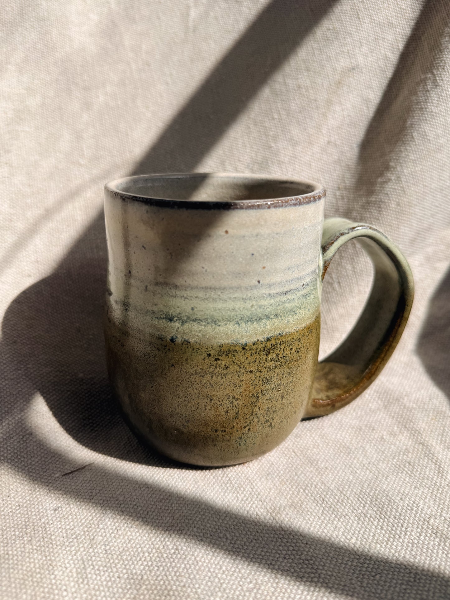Ceramic mug with gradient color on a textured fabric background