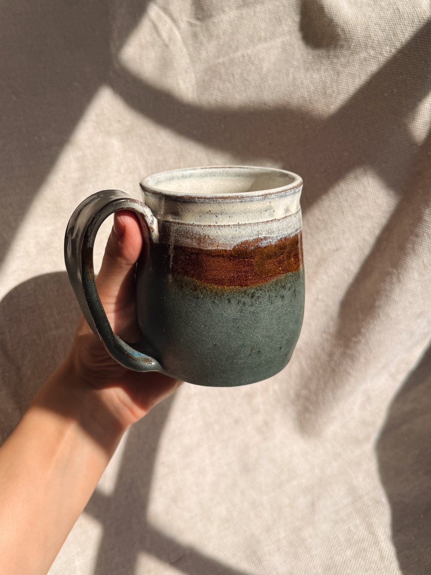 Hand holding a ceramic mug with a gradient design against a neutral background