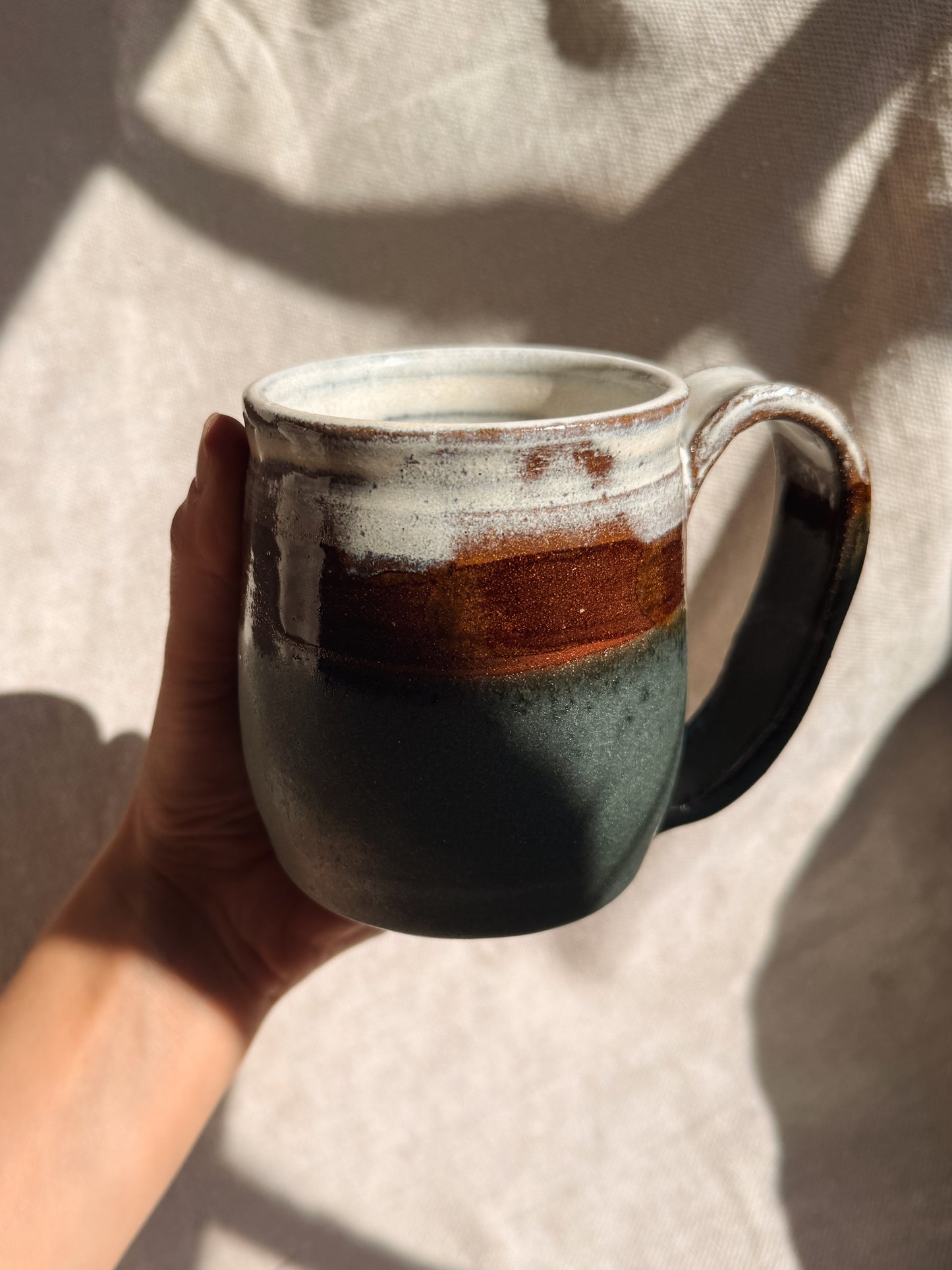 Hand holding a ceramic mug with a gradient design against a neutral background