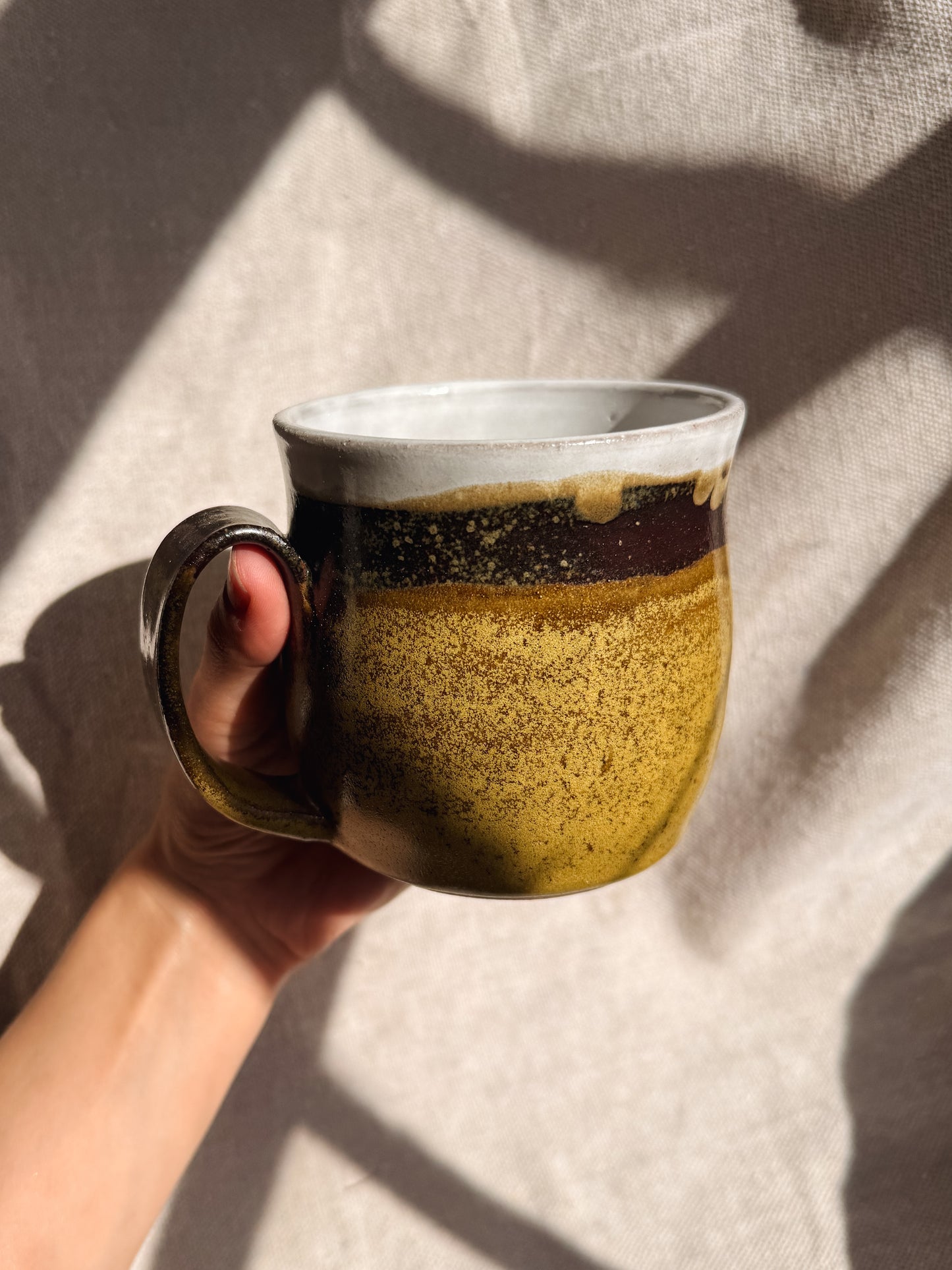 Person holding a ceramic mug  against a neutral background