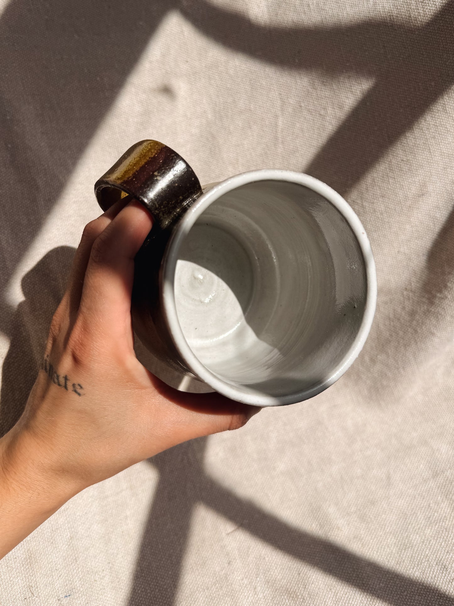 Hand holding a white ceramic mug on a textured surface