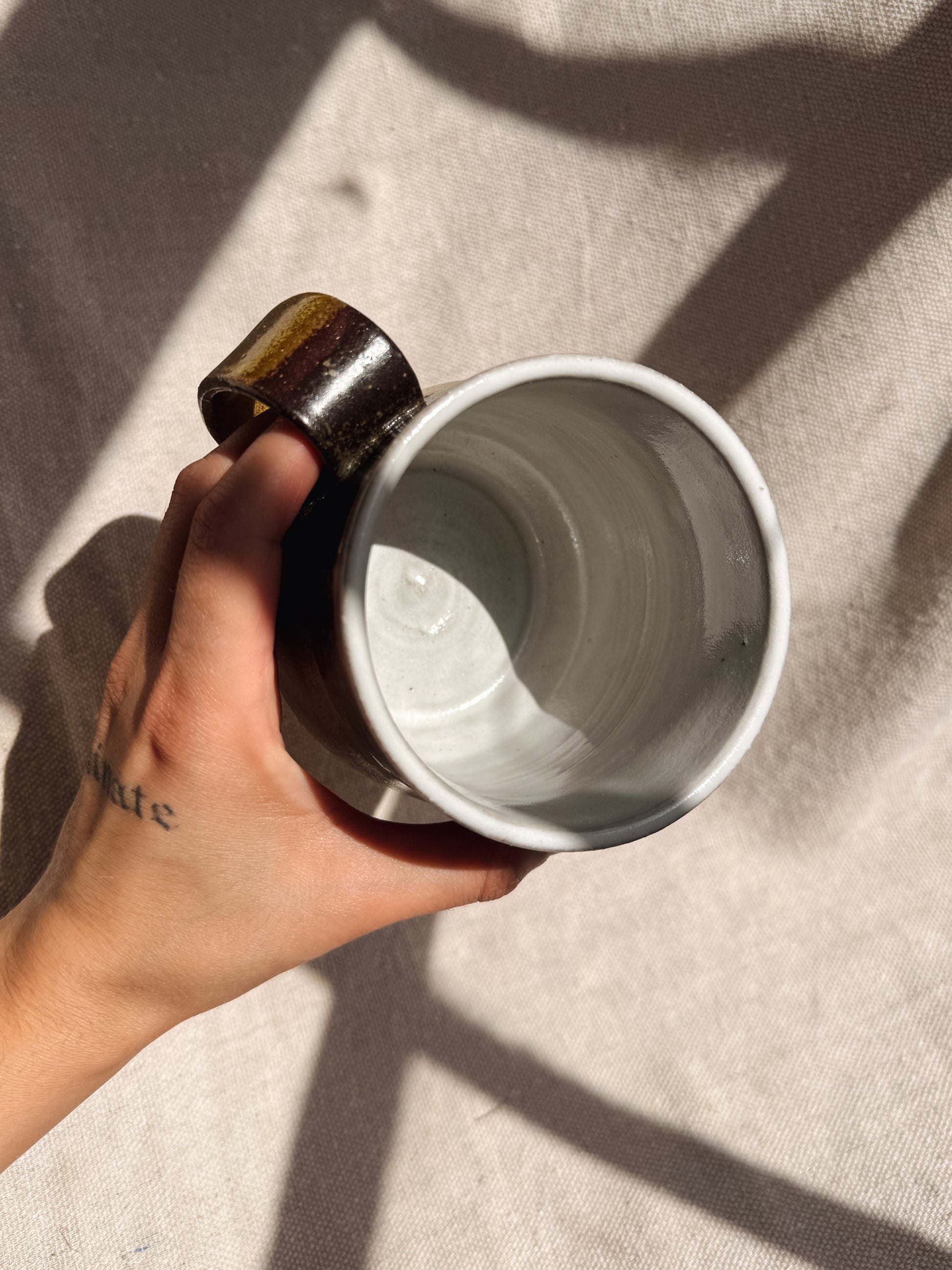 Hand holding a white ceramic mug on a textured surface
