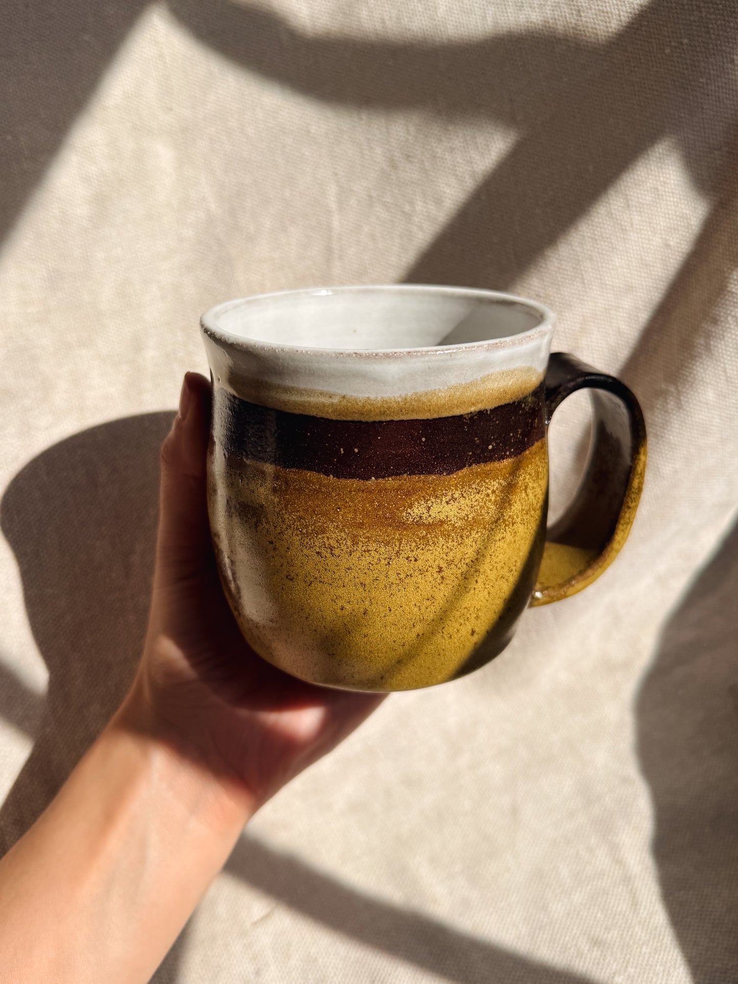 Hand holding a ceramic mug with a gradient design against a neutral background