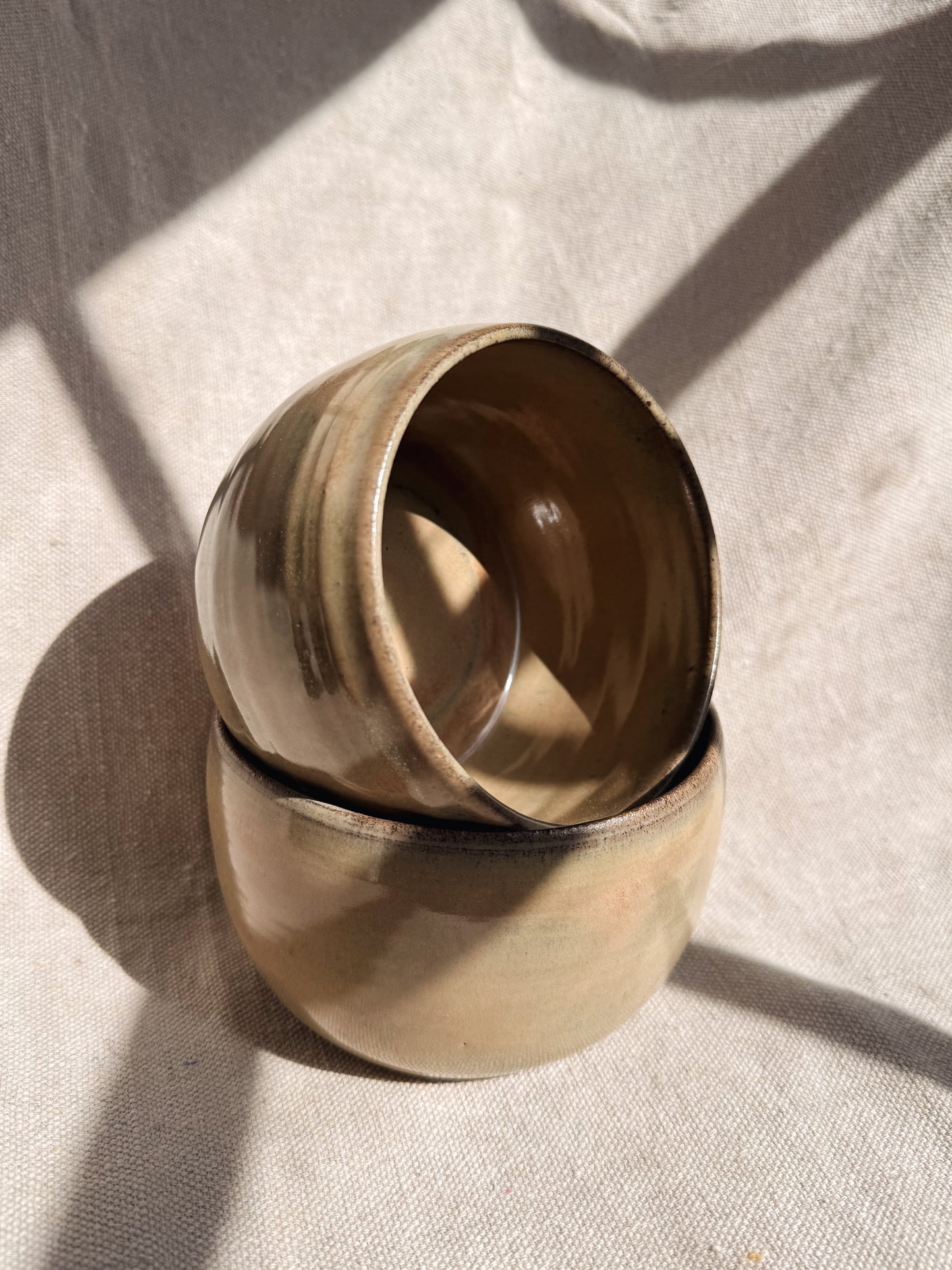 Two stacked ceramic bowls on a textured beige surface