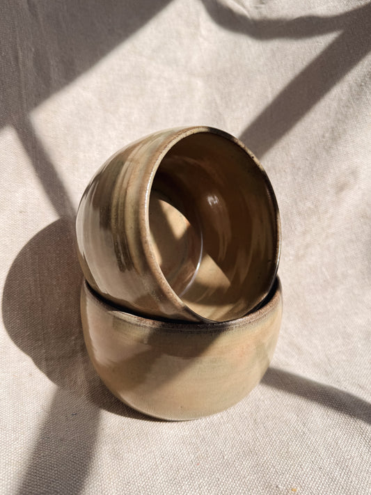 Two stacked ceramic bowls on a textured beige surface