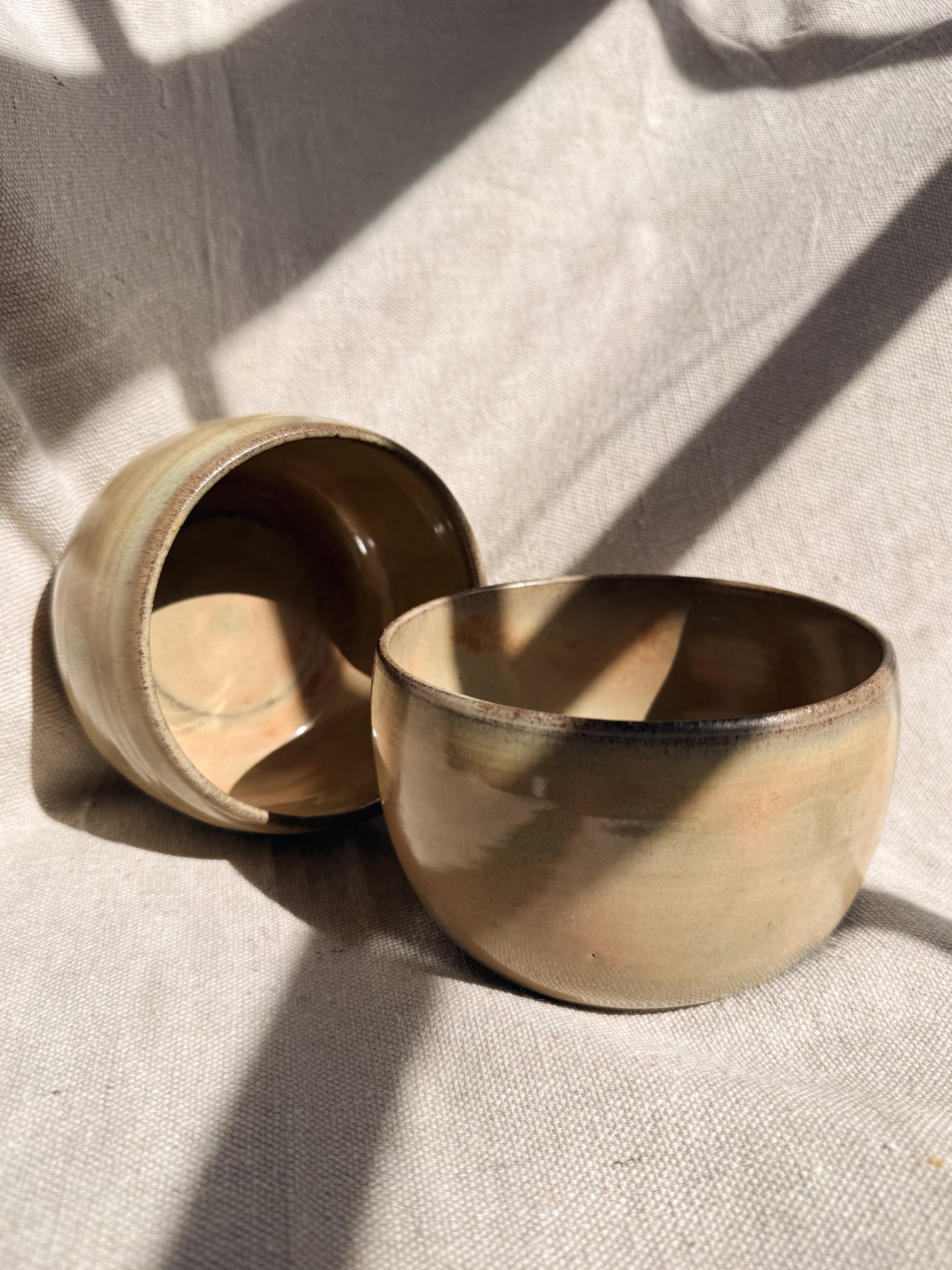 Two bowls on a textured surface with soft shadows