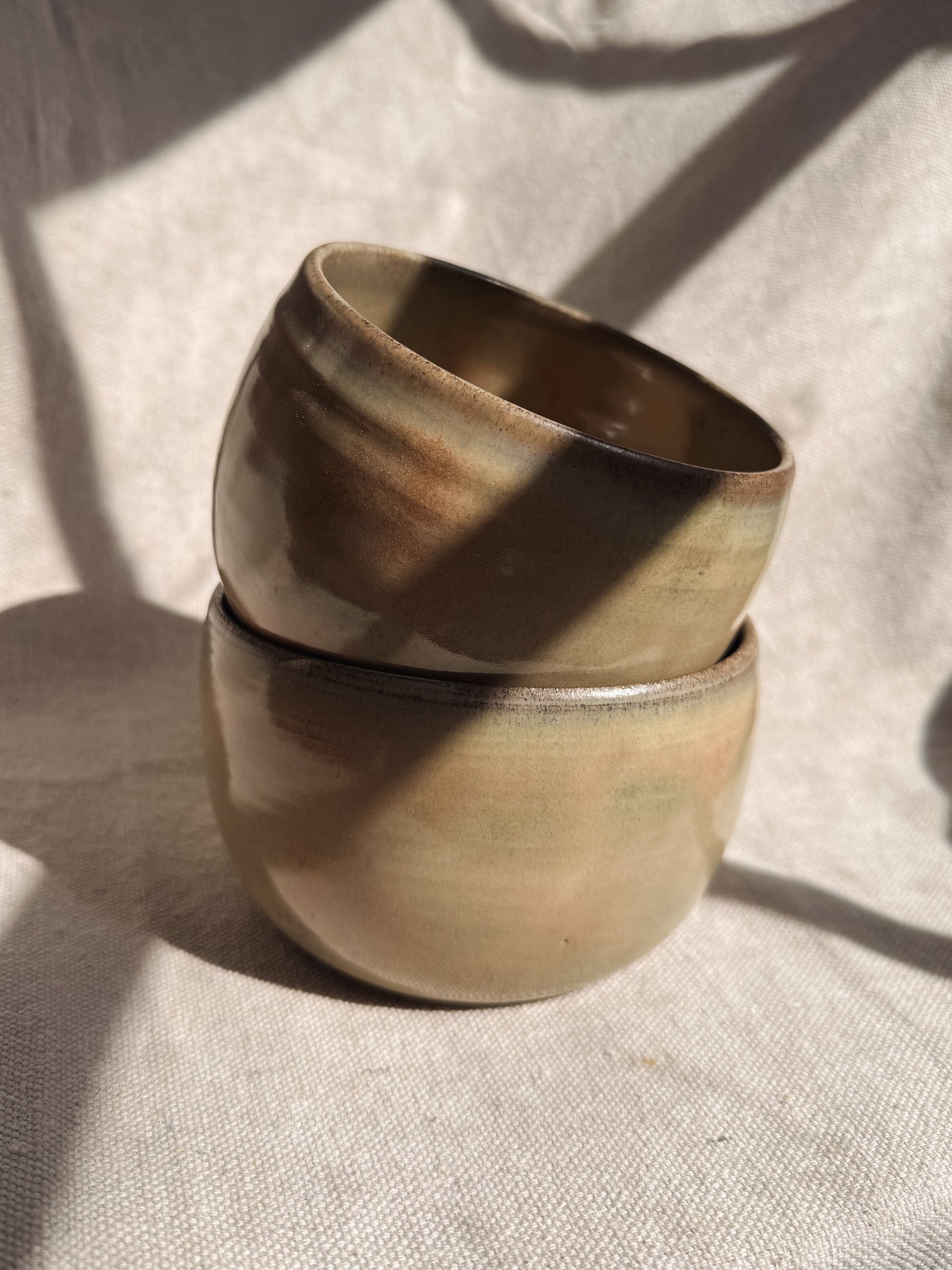 Two stacked ceramic bowls on a textured fabric surface