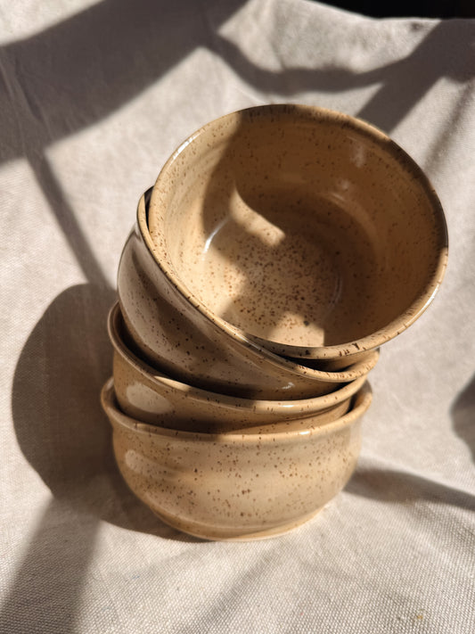 Stack of yellow ceramic bowls on a textured fabric surface