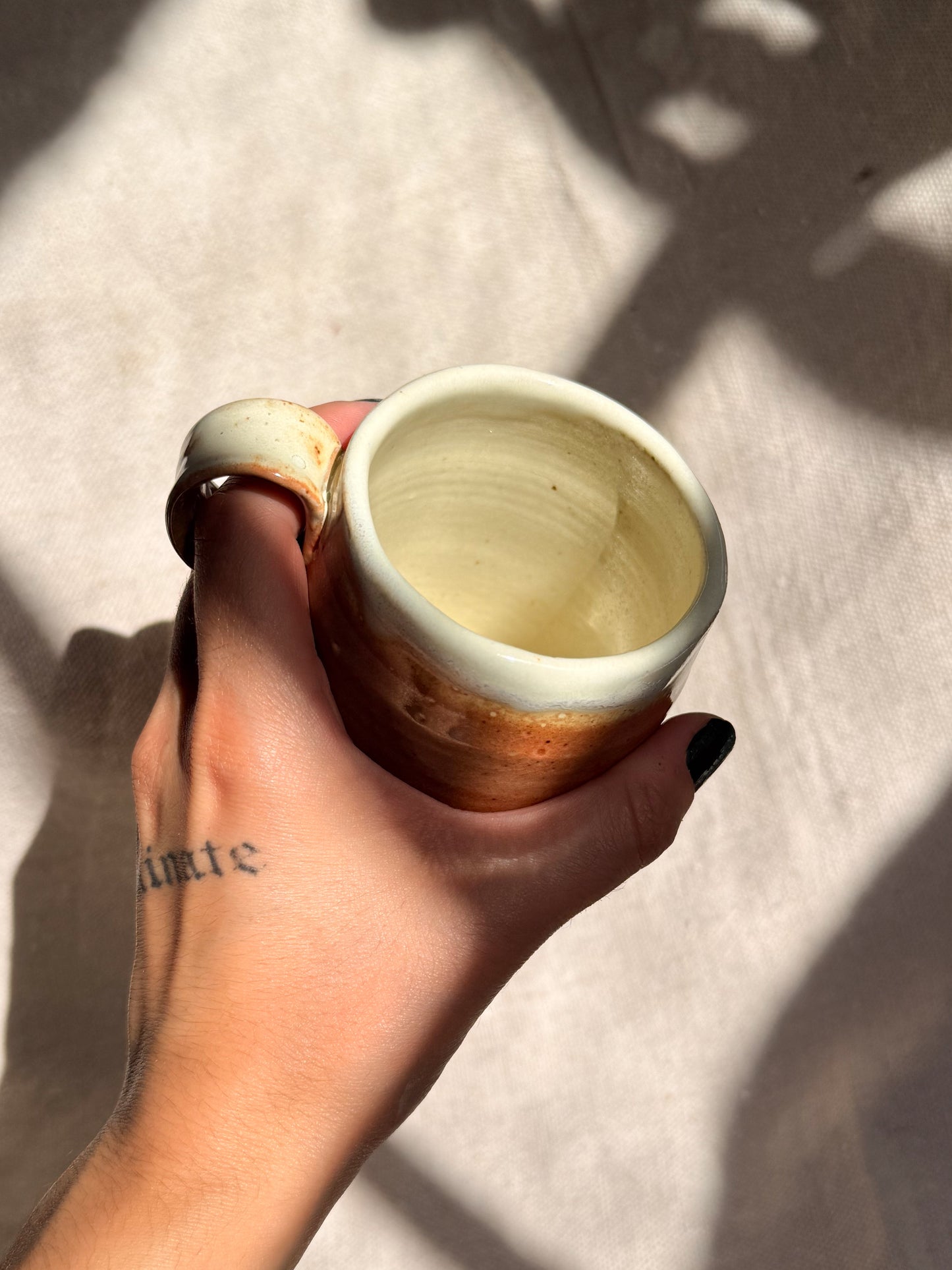 Hand holding a ceramic mug against a neutral background