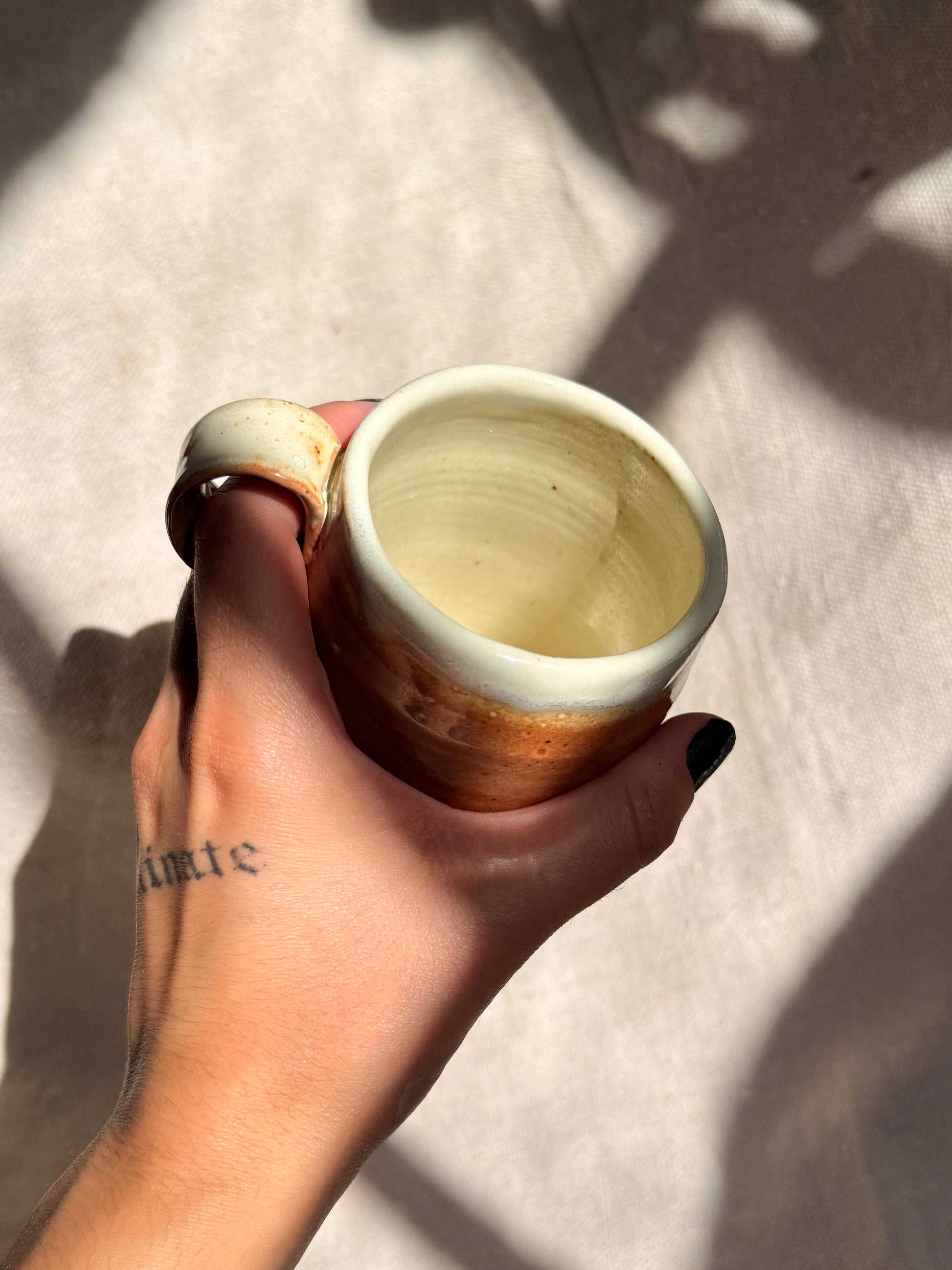 Hand holding a ceramic mug against a neutral background