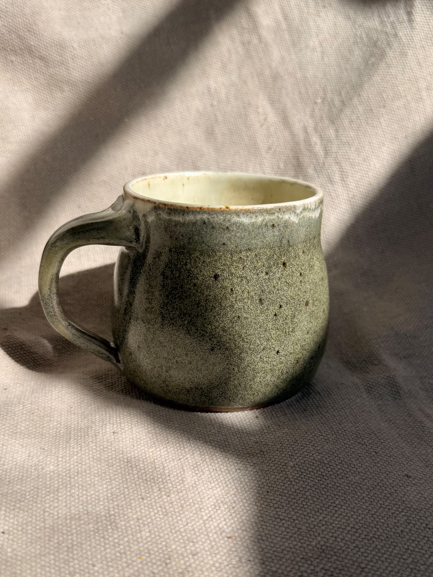 Green ceramic mug on a textured beige surface