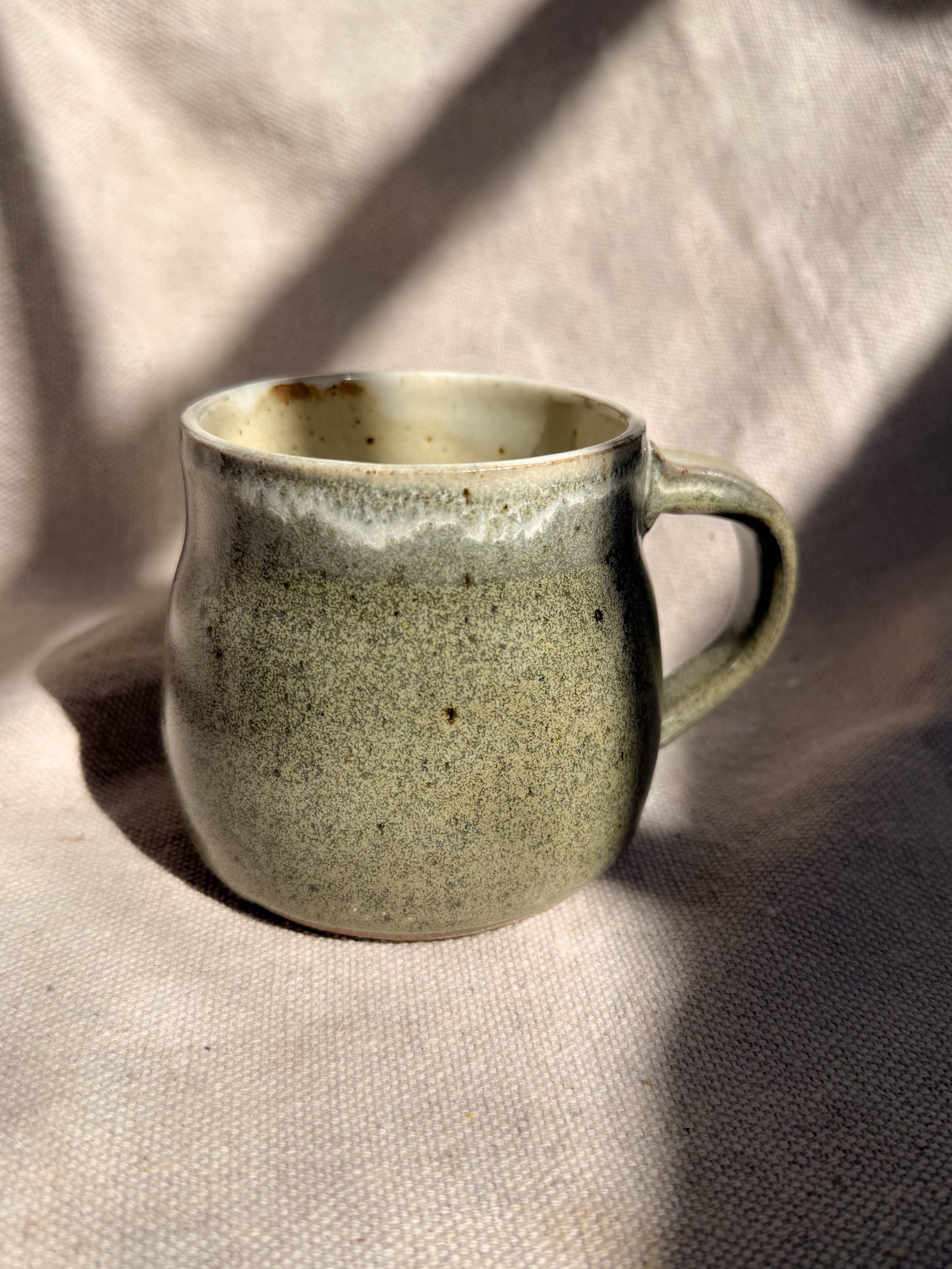 Green ceramic mug on a textured beige surface