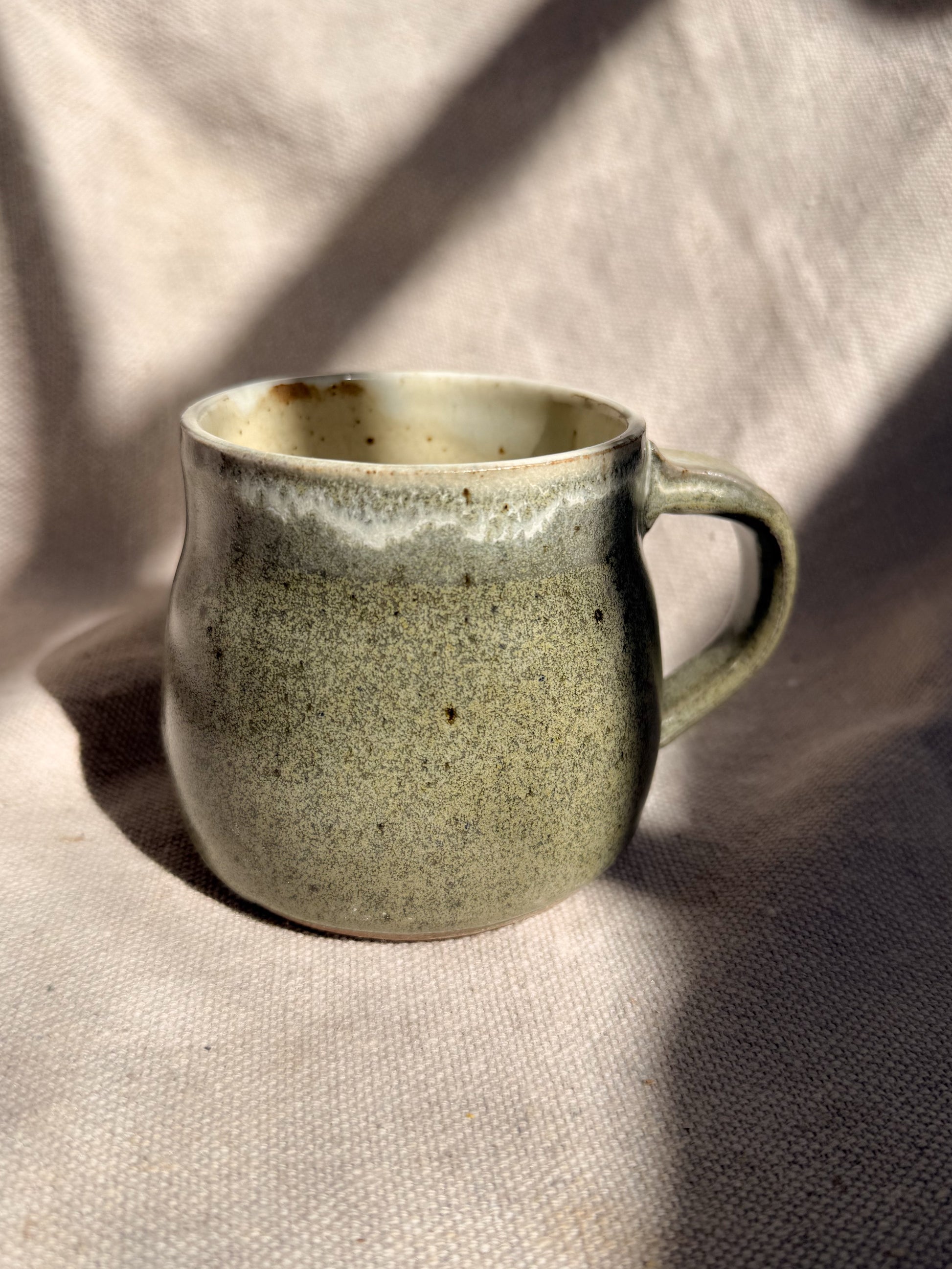 Green ceramic mug on a textured beige surface