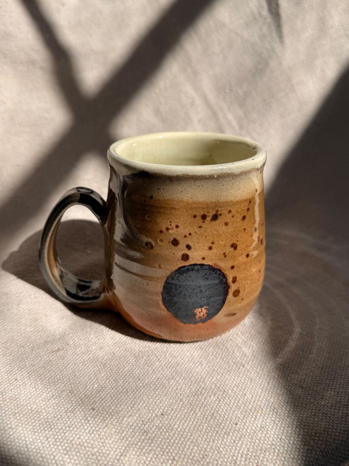 Ceramic mug with speckled design on a textured fabric background