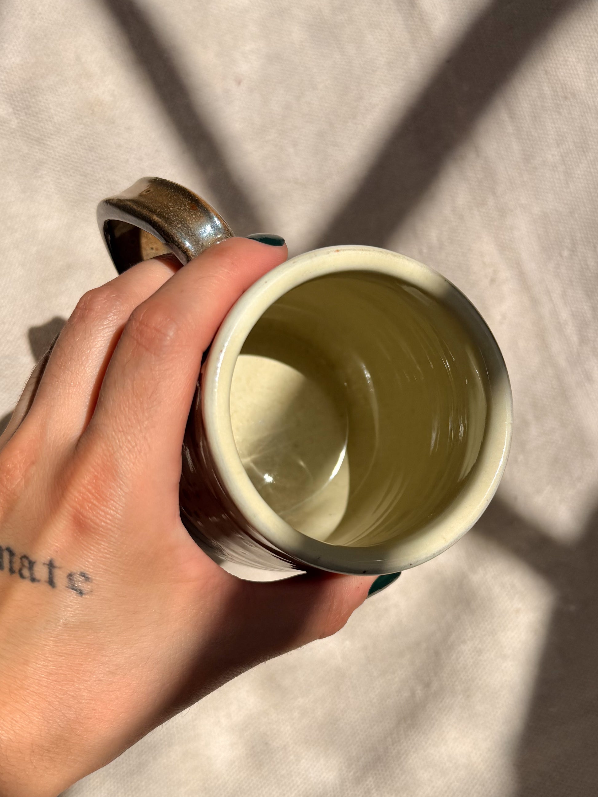 Hand holding a ceramic mug with a plain background
