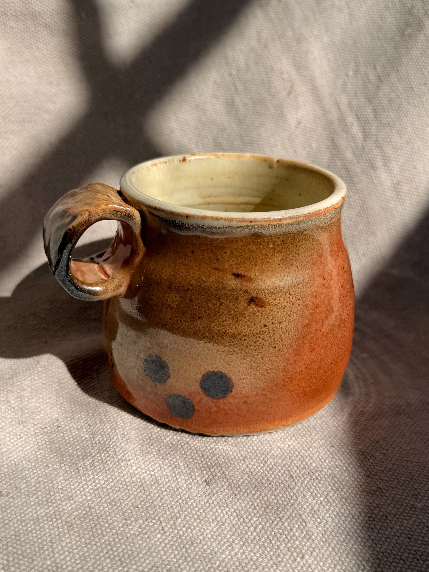 Handmade ceramic mug with a textured surface on a fabric background
