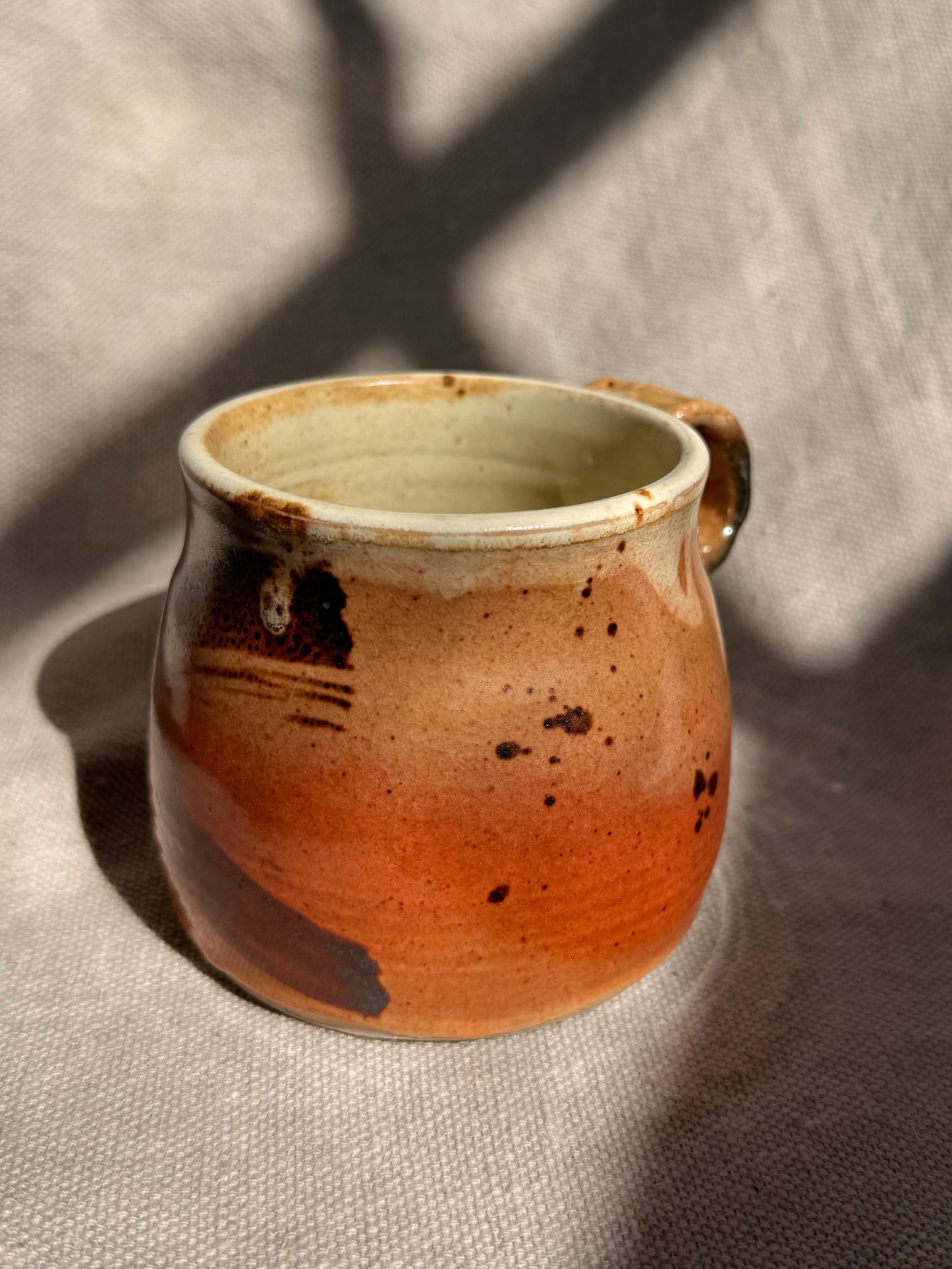 Ceramic mug with a gradient from brown to beige on a textured surface