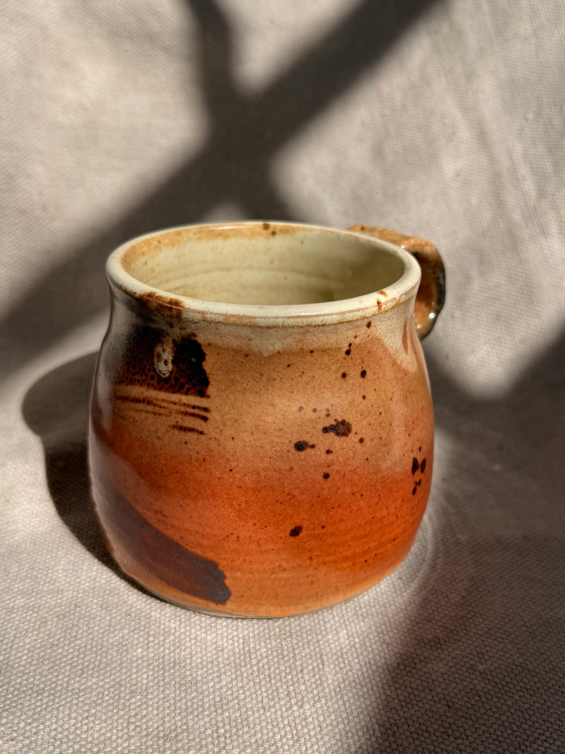 Ceramic mug with a gradient from brown to beige on a textured surface