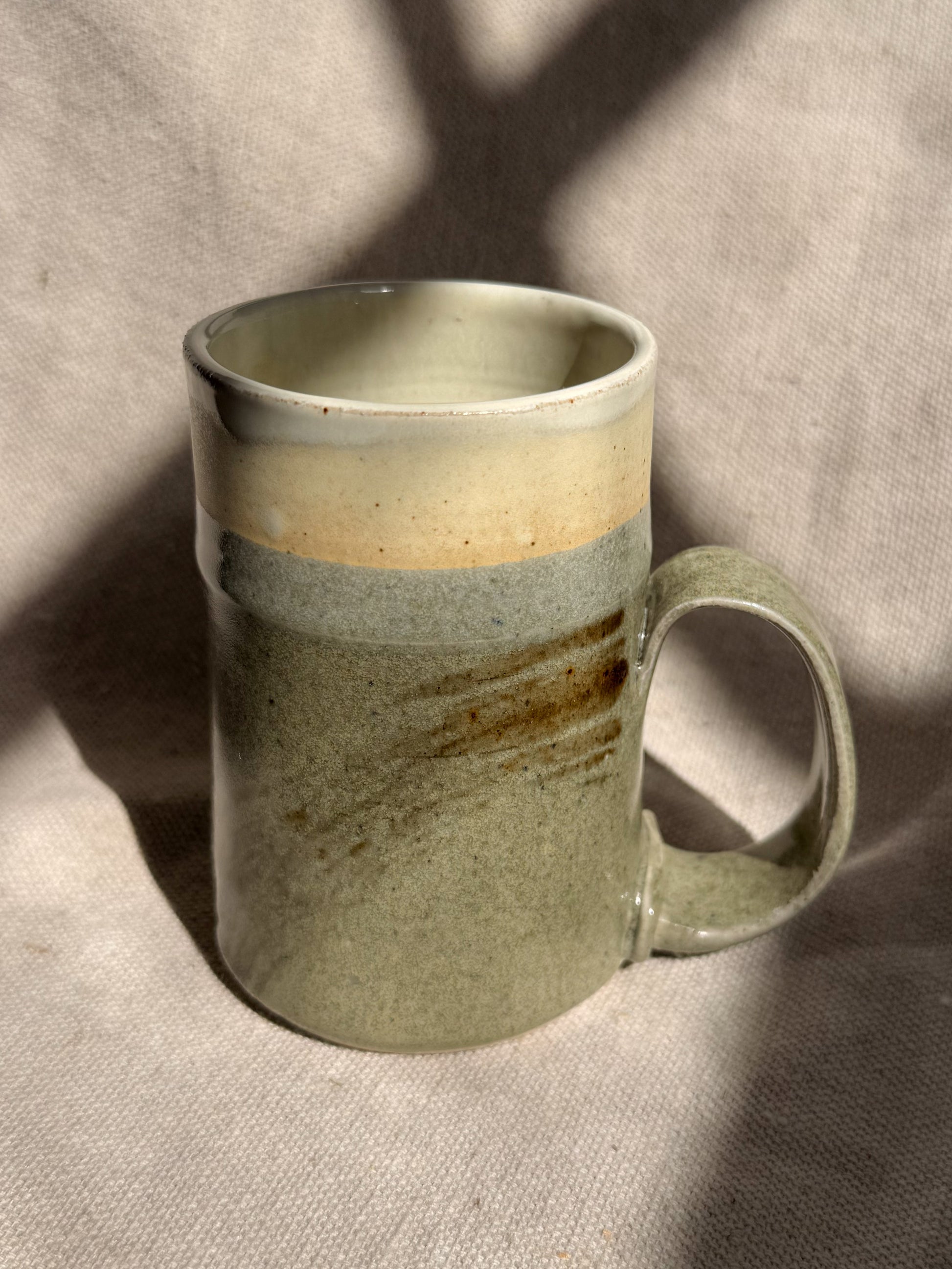 Green ceramic mug with a textured surface on a beige fabric background