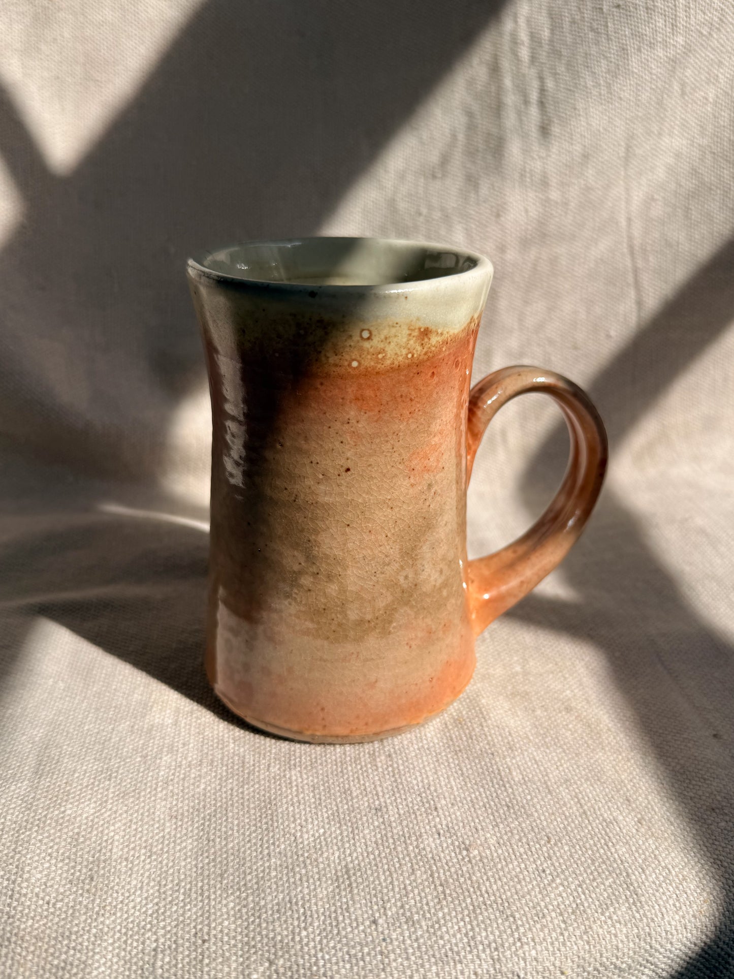 Ceramic mug with gradient color on a textured surface