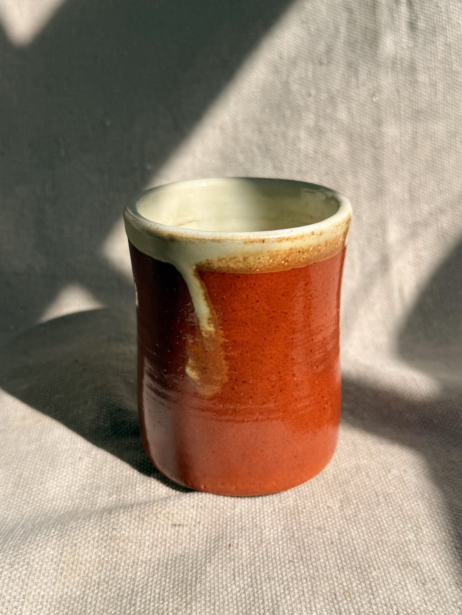 Ceramic cup with a gradient from green to red on a textured surface