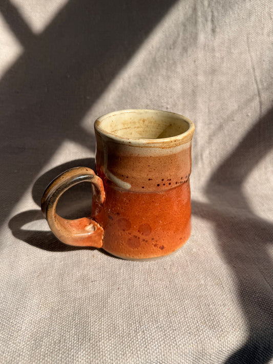 Ceramic mug with a gradient from brown to beige on a textured fabric background