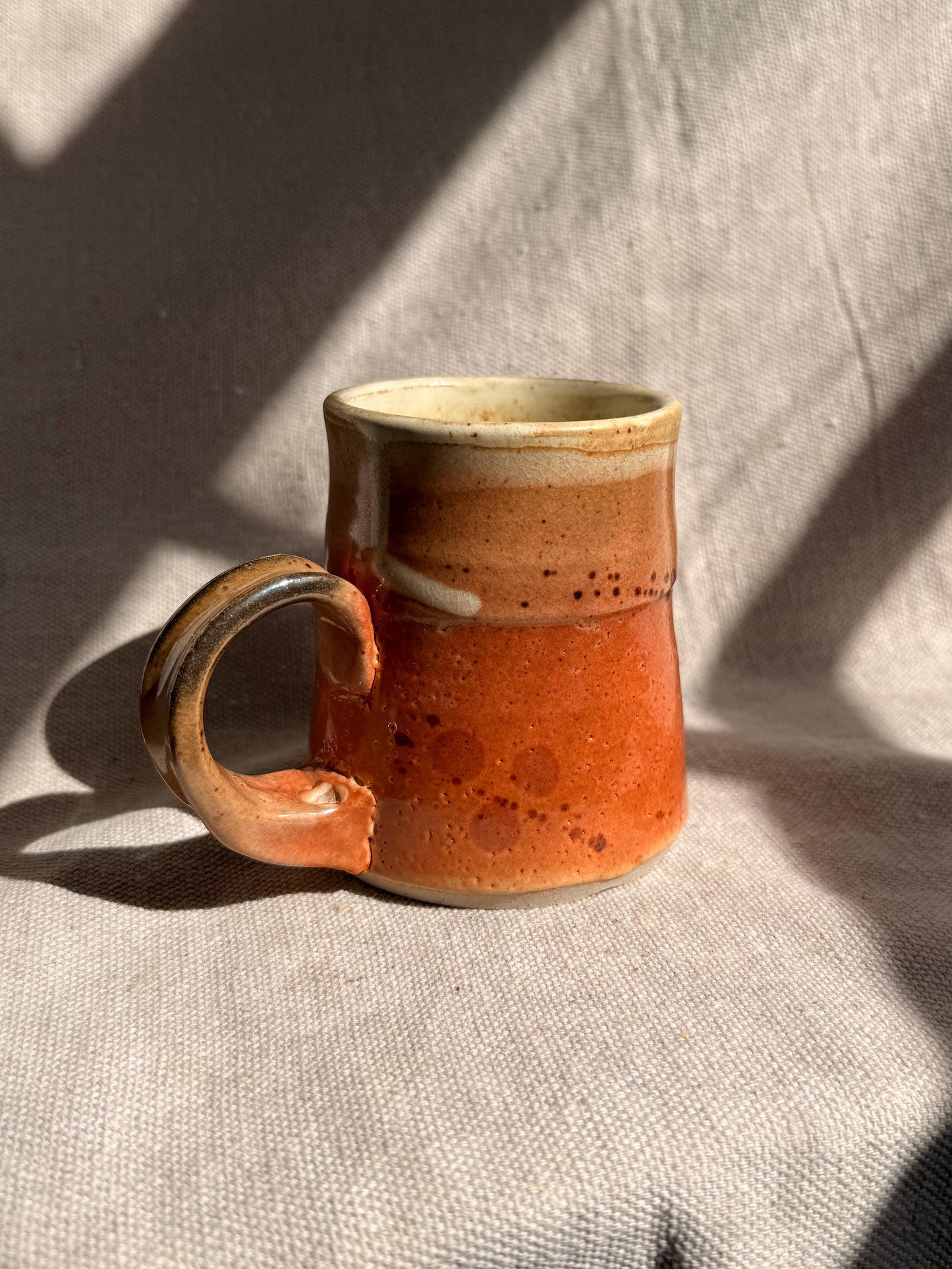 Ceramic mug with brown glaze on a textured surface