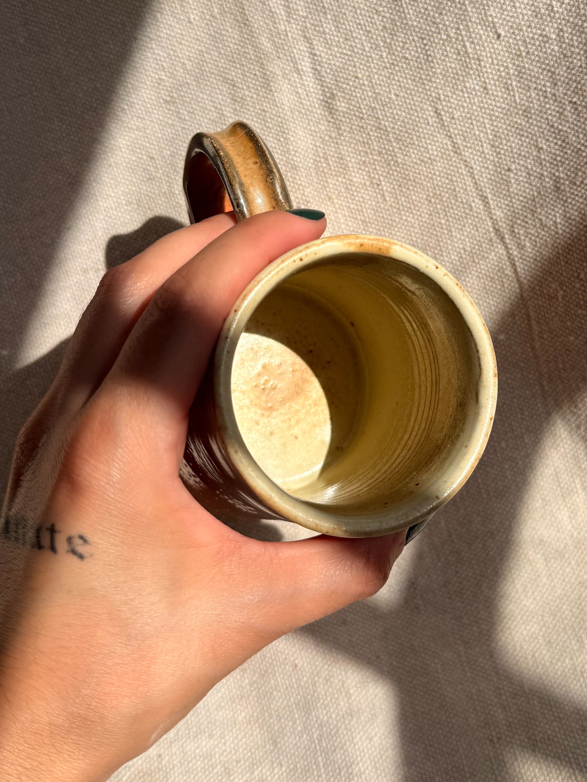 Hand holding a ceramic mug with a textured interior against a neutral background