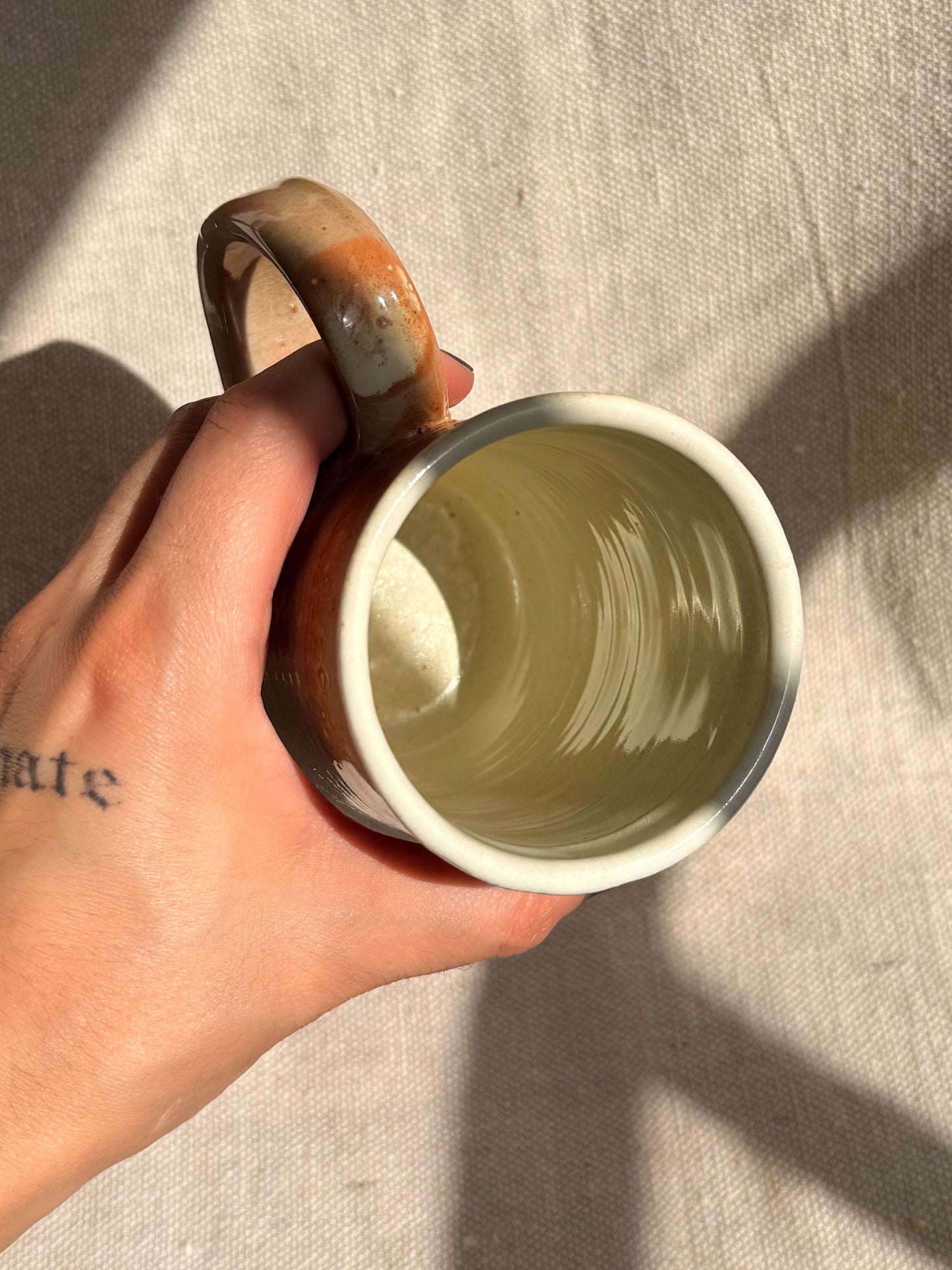 Hand holding a ceramic mug with a textured interior against a neutral background