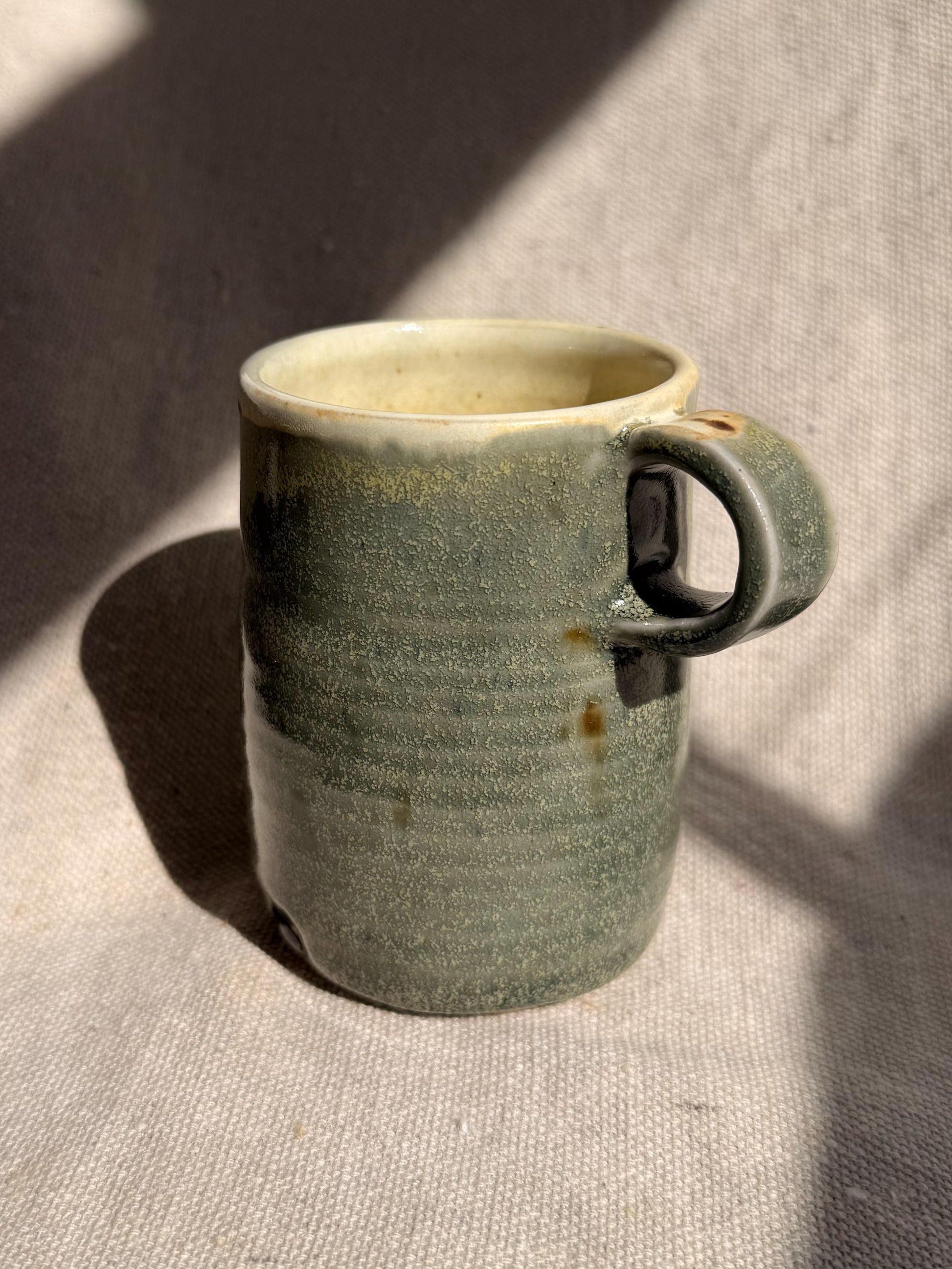 Green ceramic mug on a textured surface